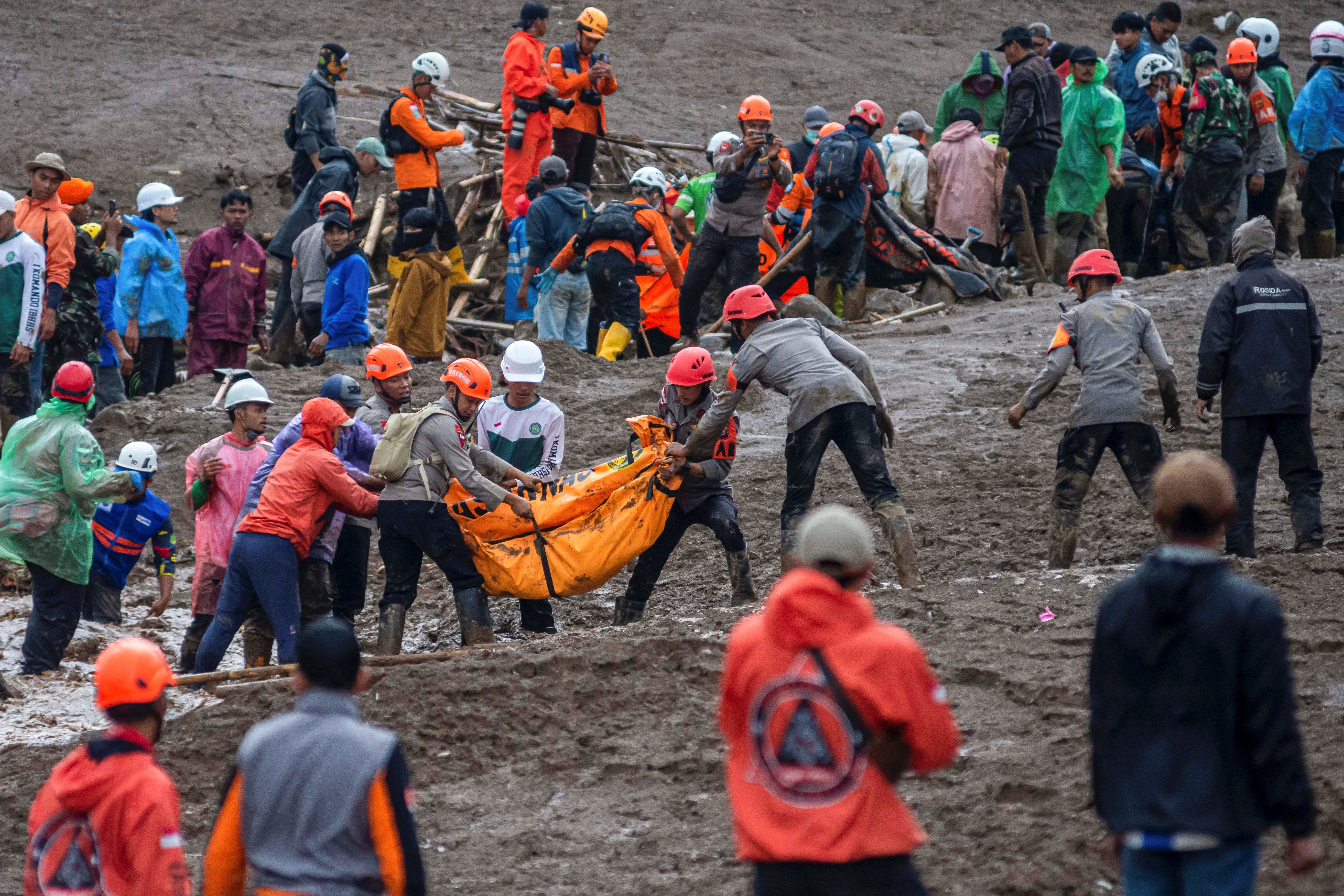 Indonesian rescue members carry a body bag containing the remains of a victim from the site