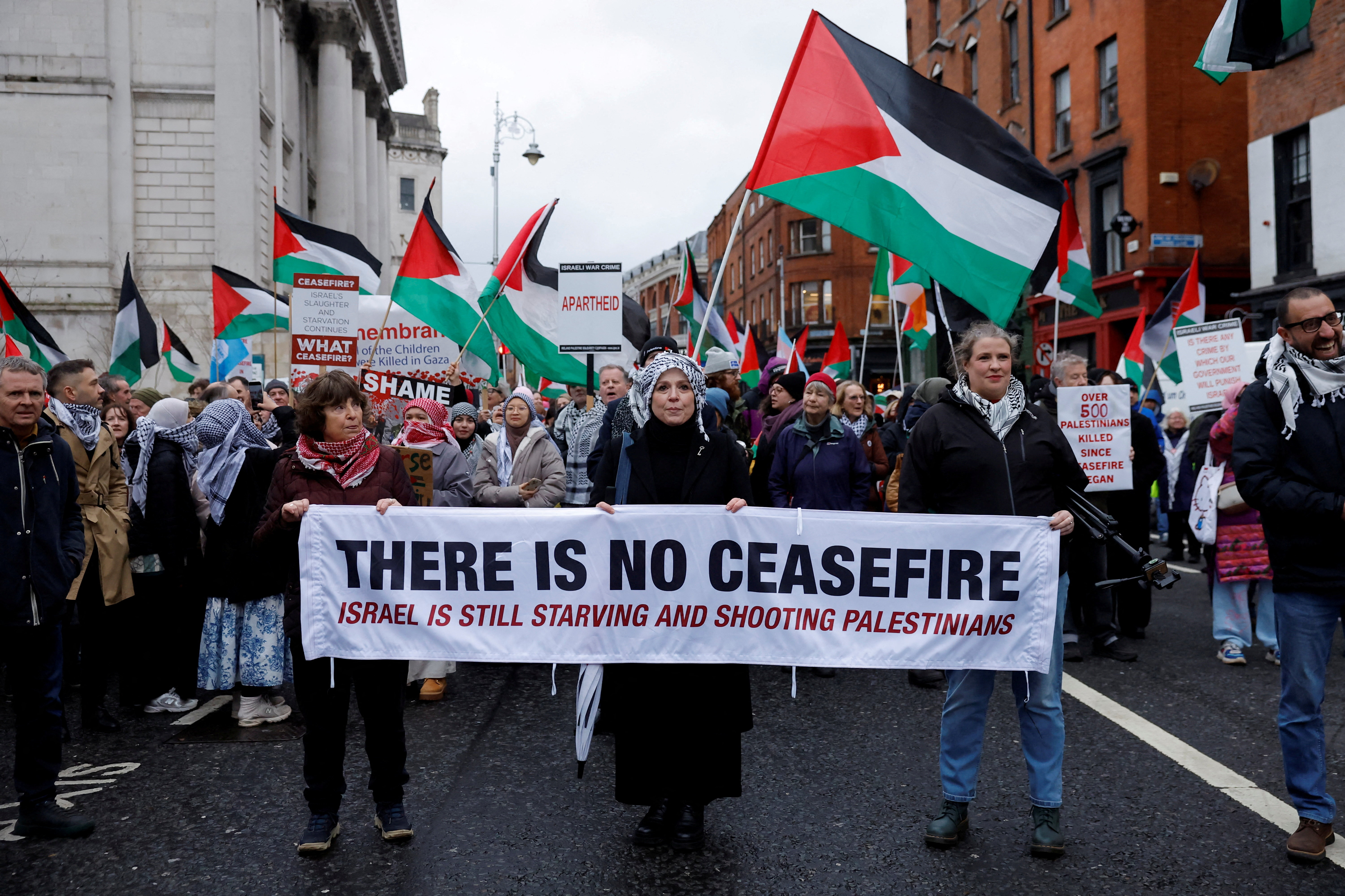 Demonstrators hold a banner and flags in support of Palestinians during a protest in relation to the ceasefire in Gaza, in Dublin, Ireland
