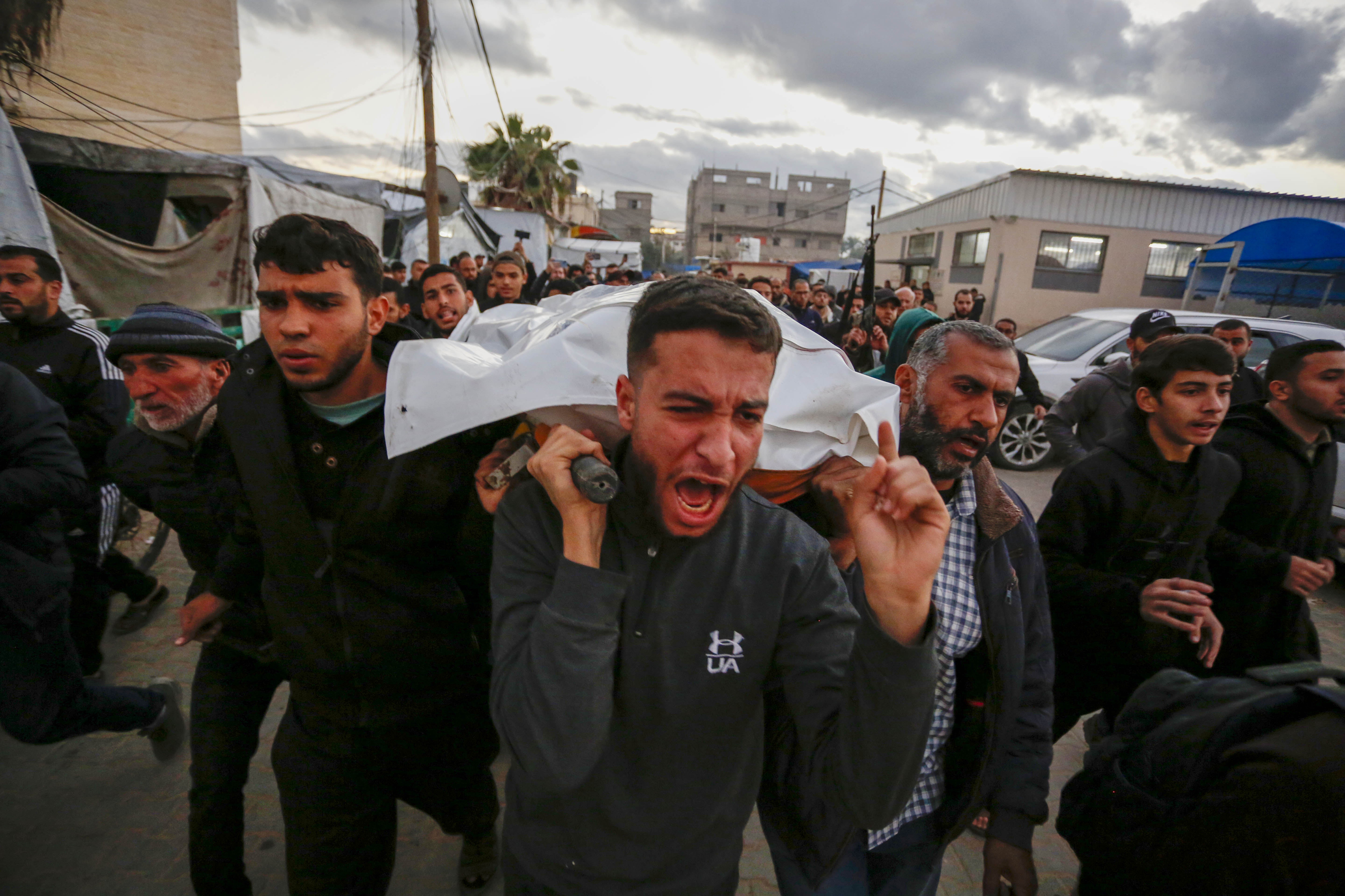 People in Gaza attend a funeral as young men carry the body.