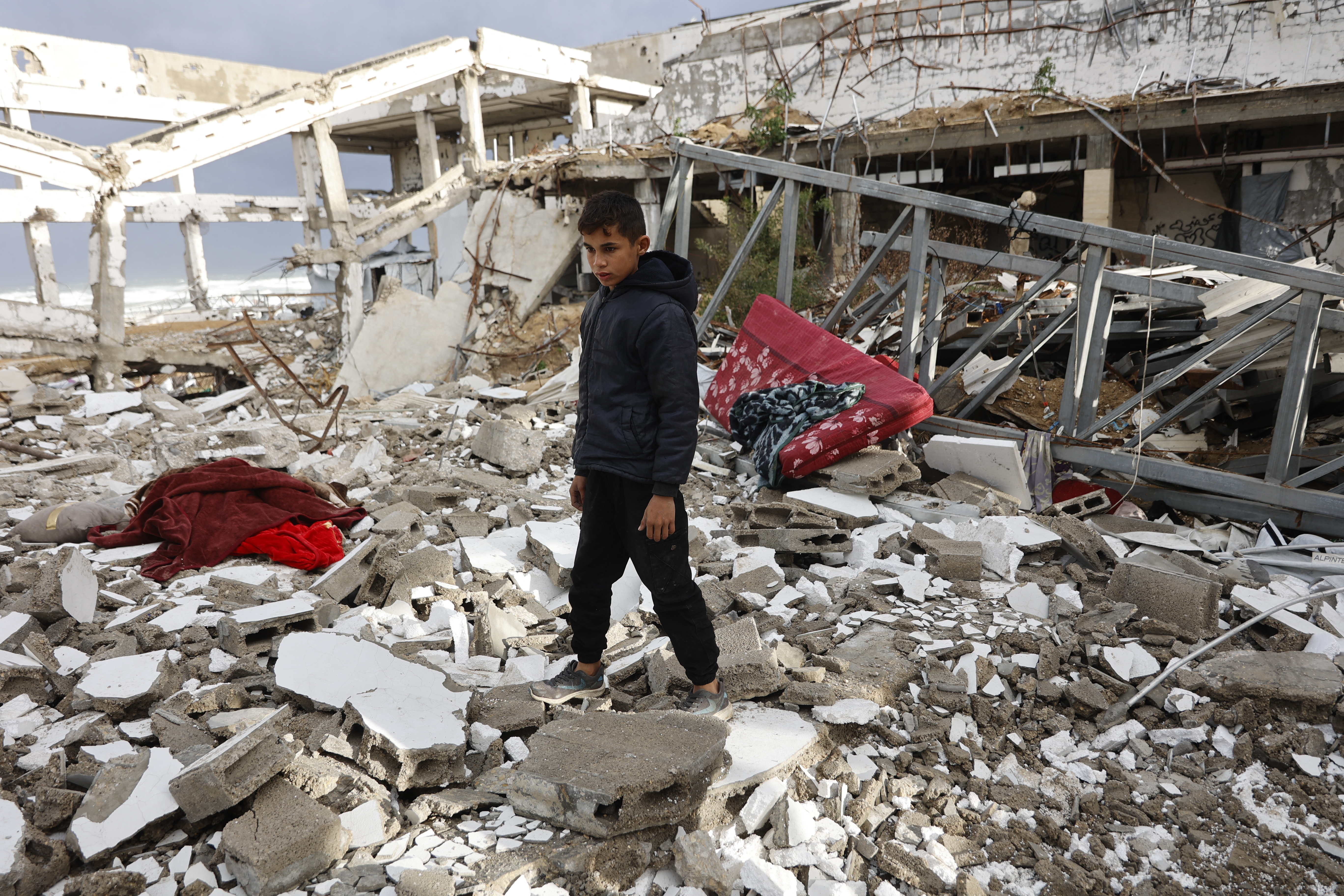 A Palestinian boy stands amid the rubble inside a war-damaged building, parts of which collapsed