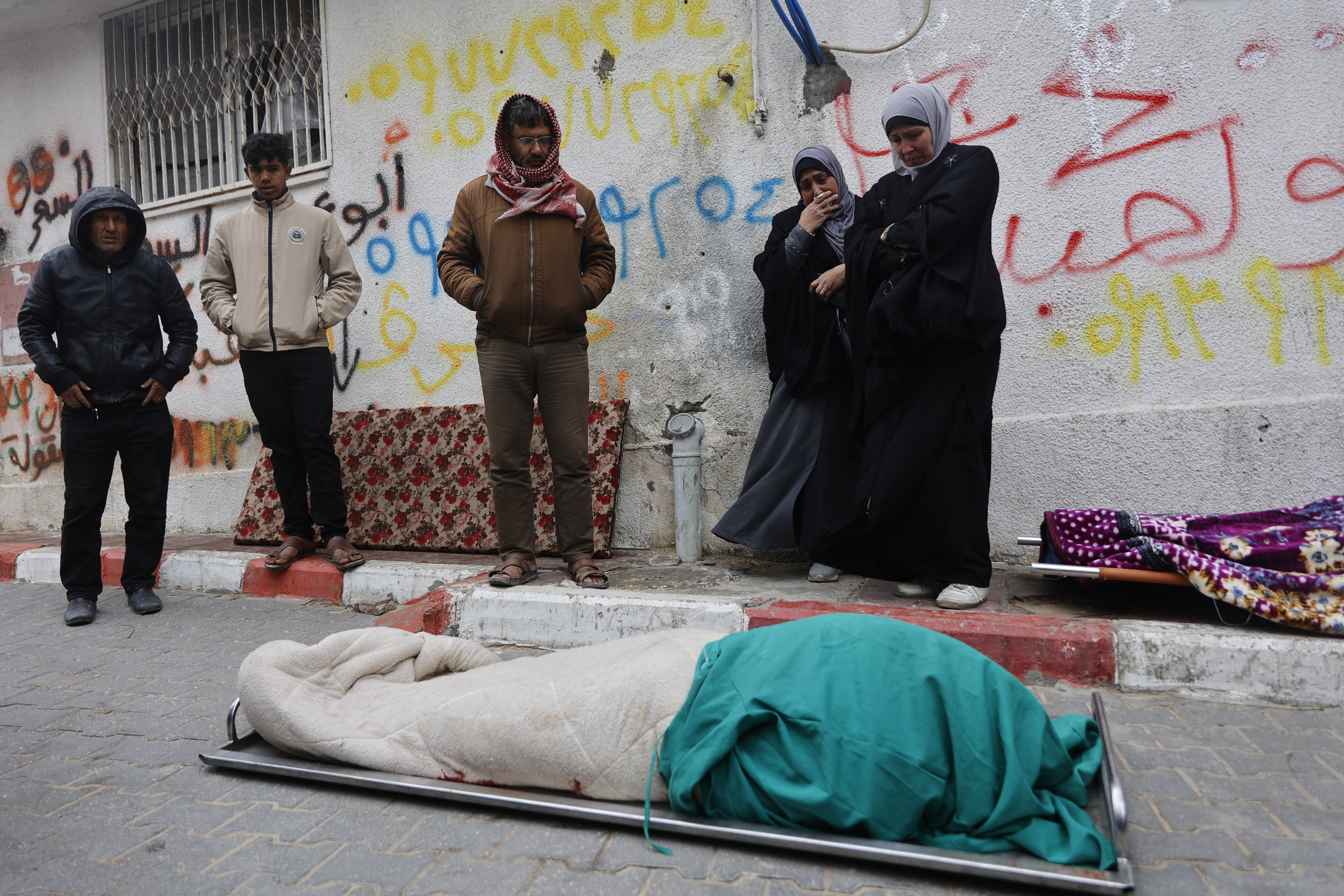 Palestinians mourn over a body during the funeral of three displaced members of the Hamoda family who died after parts of a war-damaged building