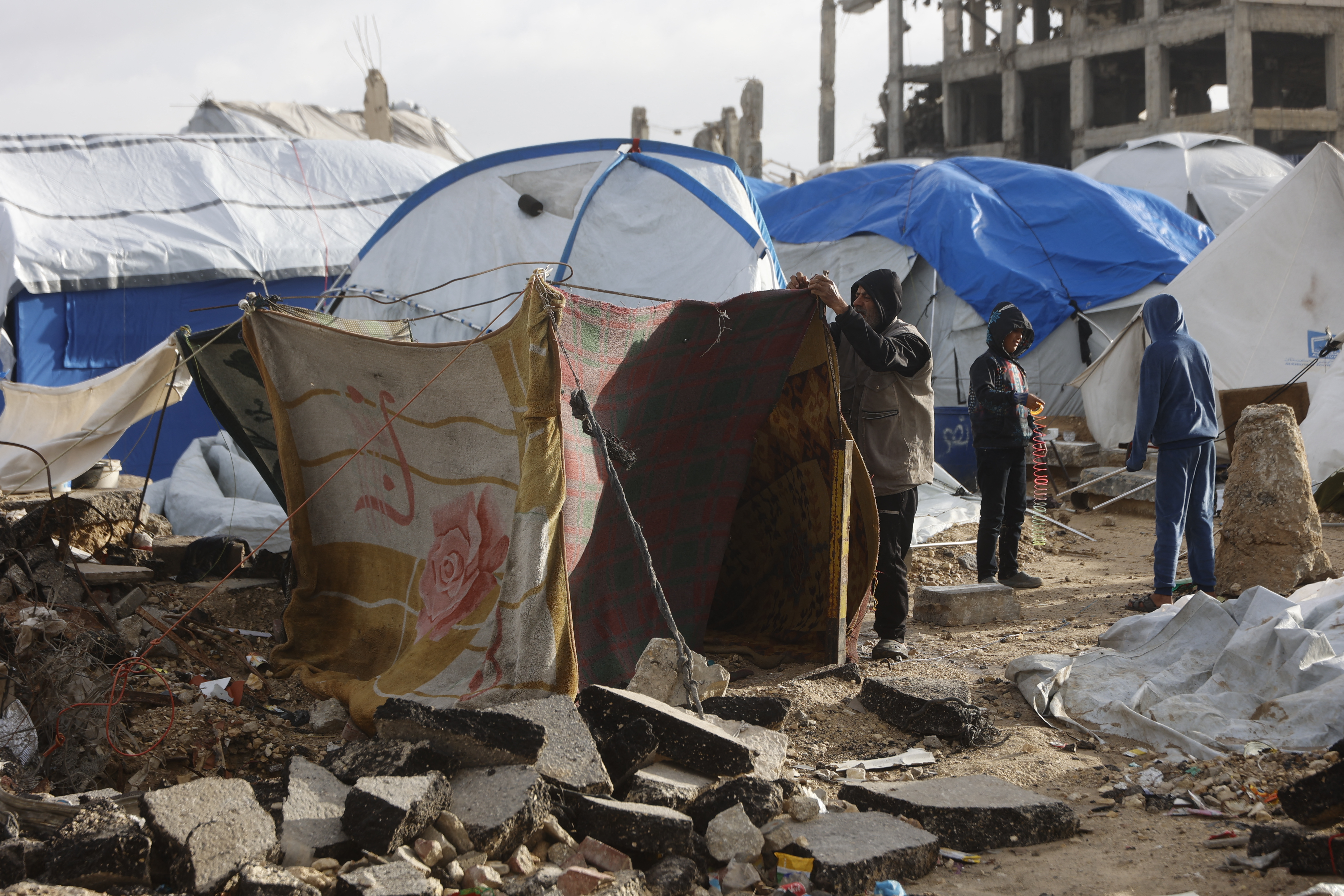 A displaced man fixes a tent shelter set up along the shore in Gaza City as strong winter winds sweep the Palestinian enclave