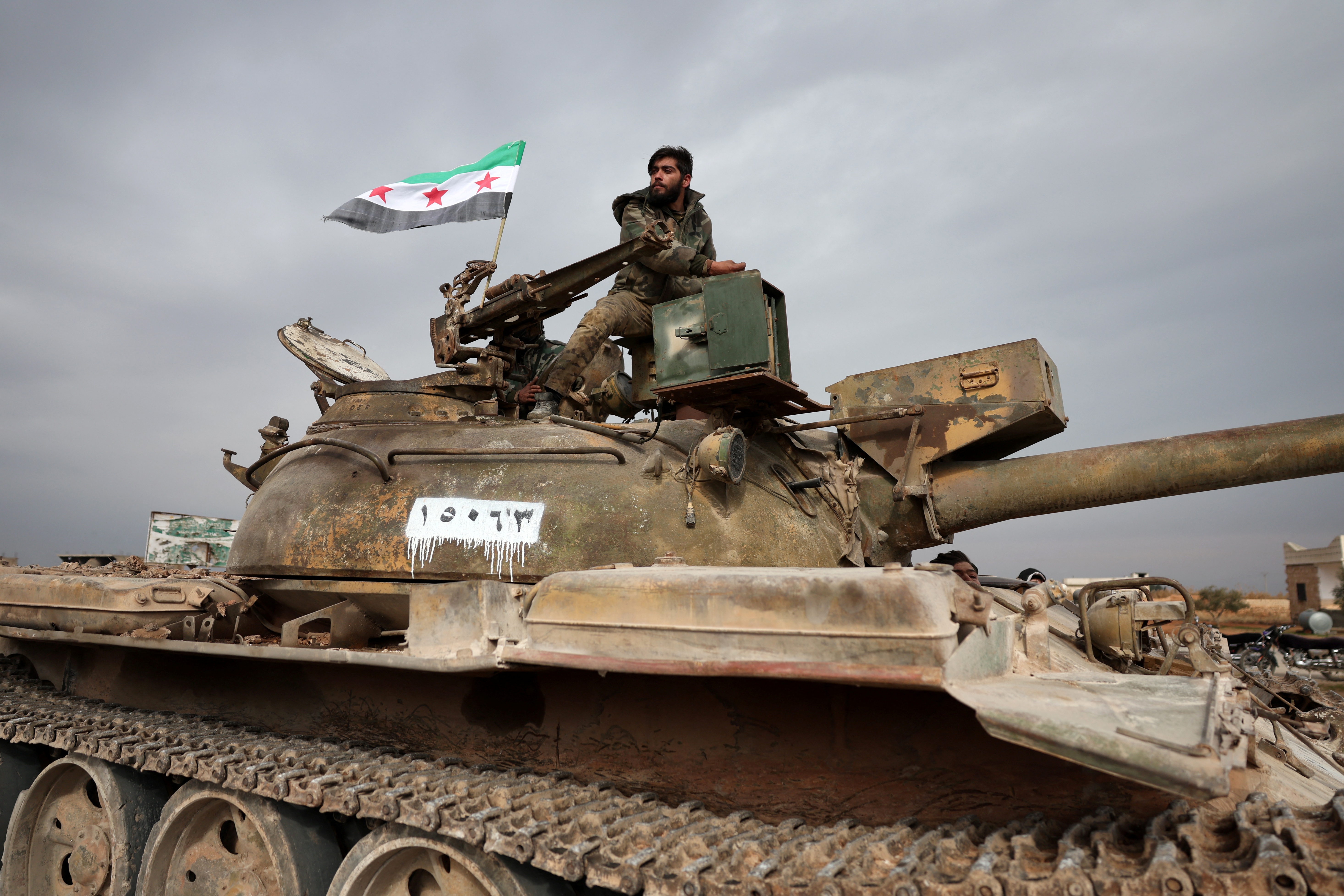 Syrian soldiers ride a tank as they replace Kurdish forces after their withdrawal from Maskana, northern Syria on January 17, 2026. Syria's army said January 17, that its forces had taken control of swathes of the region east of Aleppo city after Kurdish forces agreed to withdraw following recent clashes. (Photo by OMAR HAJ KADOUR / AFP)