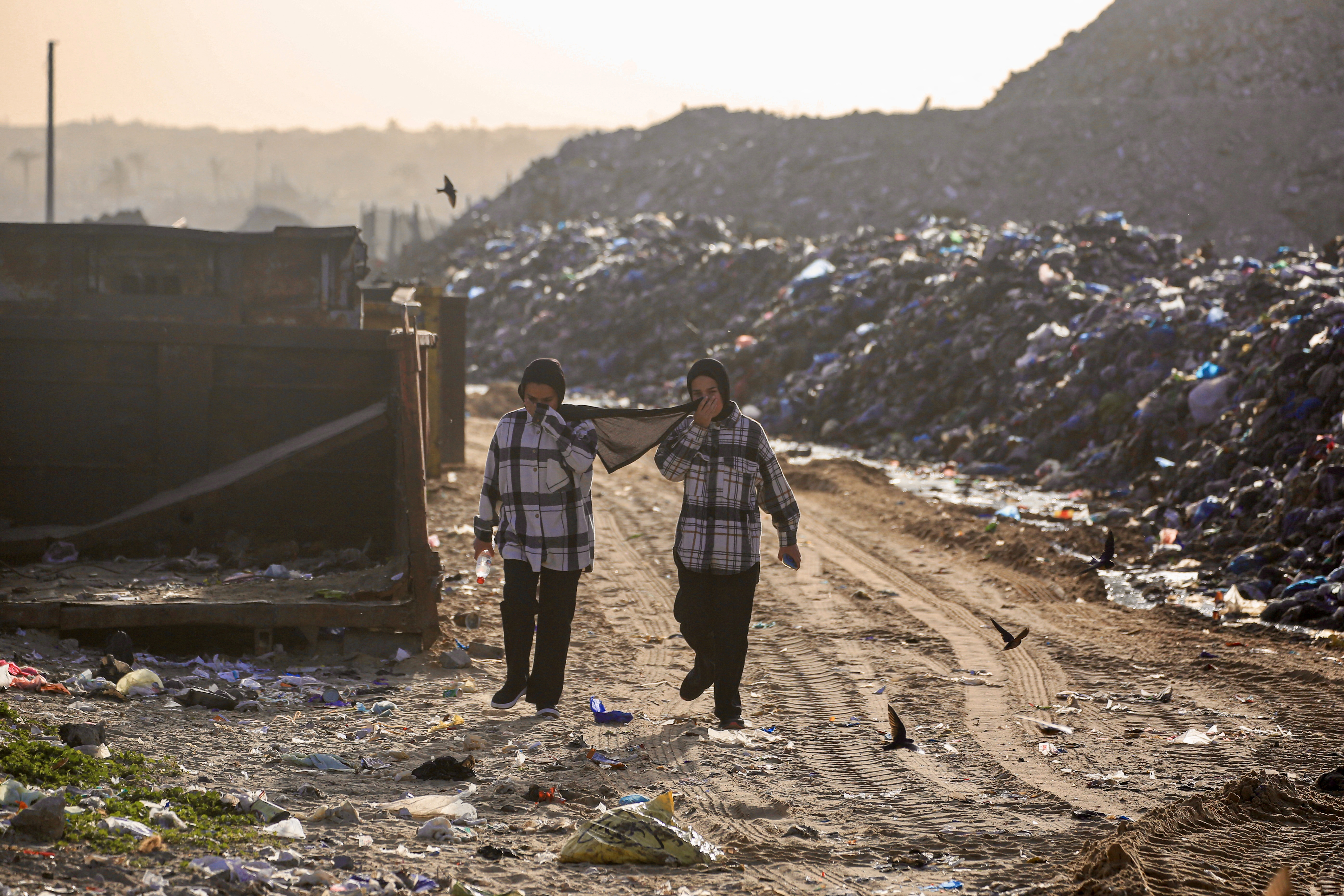 Palestinian women walk through a landfill in Khan Yunis, in the southern Gaza Strip on January 25, 2026. Since October 10, a fragile US-sponsored truce in Gaza has largely halted the fighting between Israeli forces and Hamas, but both sides have alleged frequent violations. [Photo by Bashar Taleb / AFP]