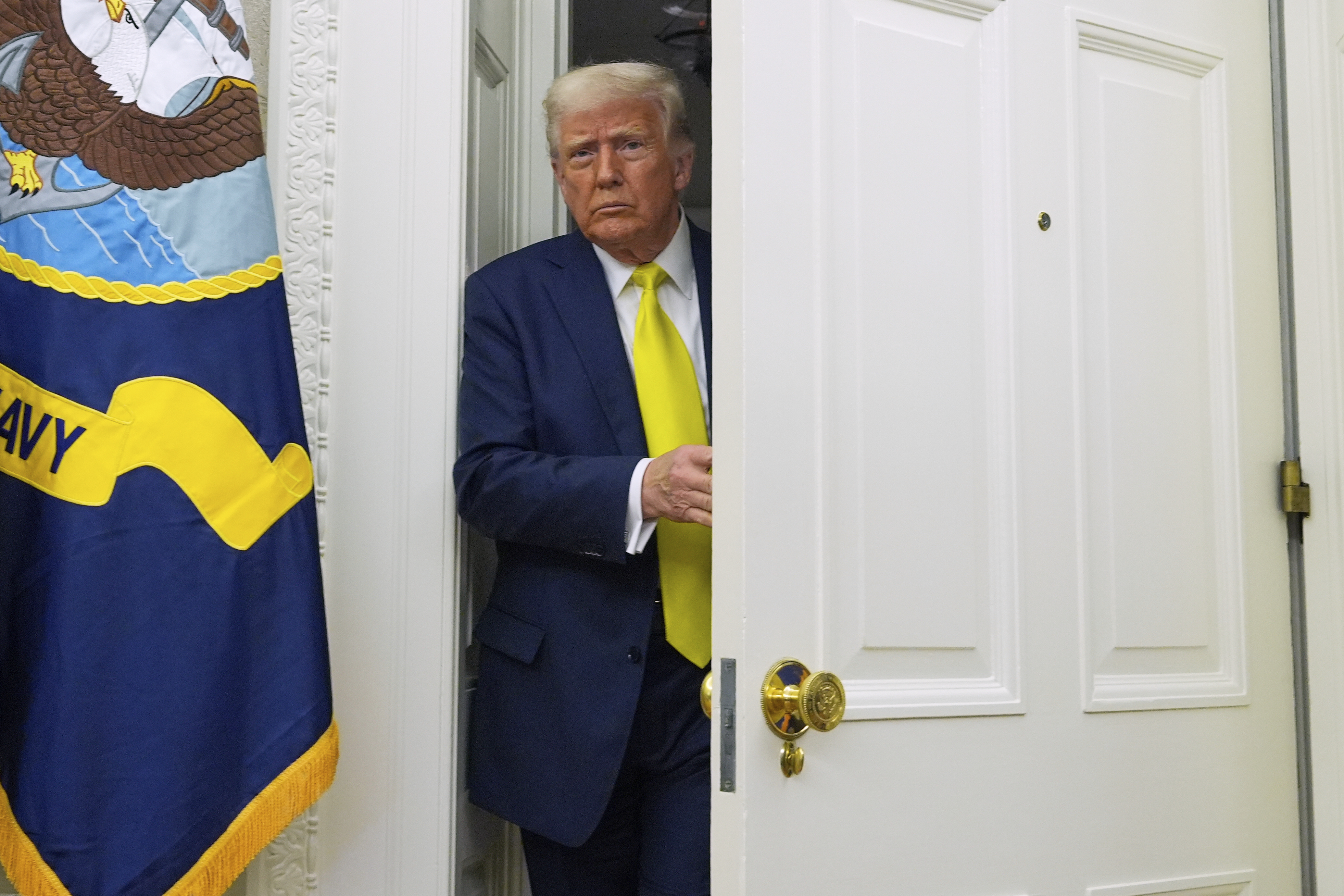 Trump steps out from a door in the White House