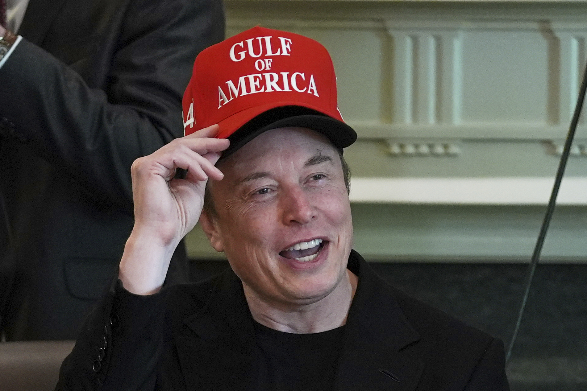 Elon Musk piles baseball caps on his head