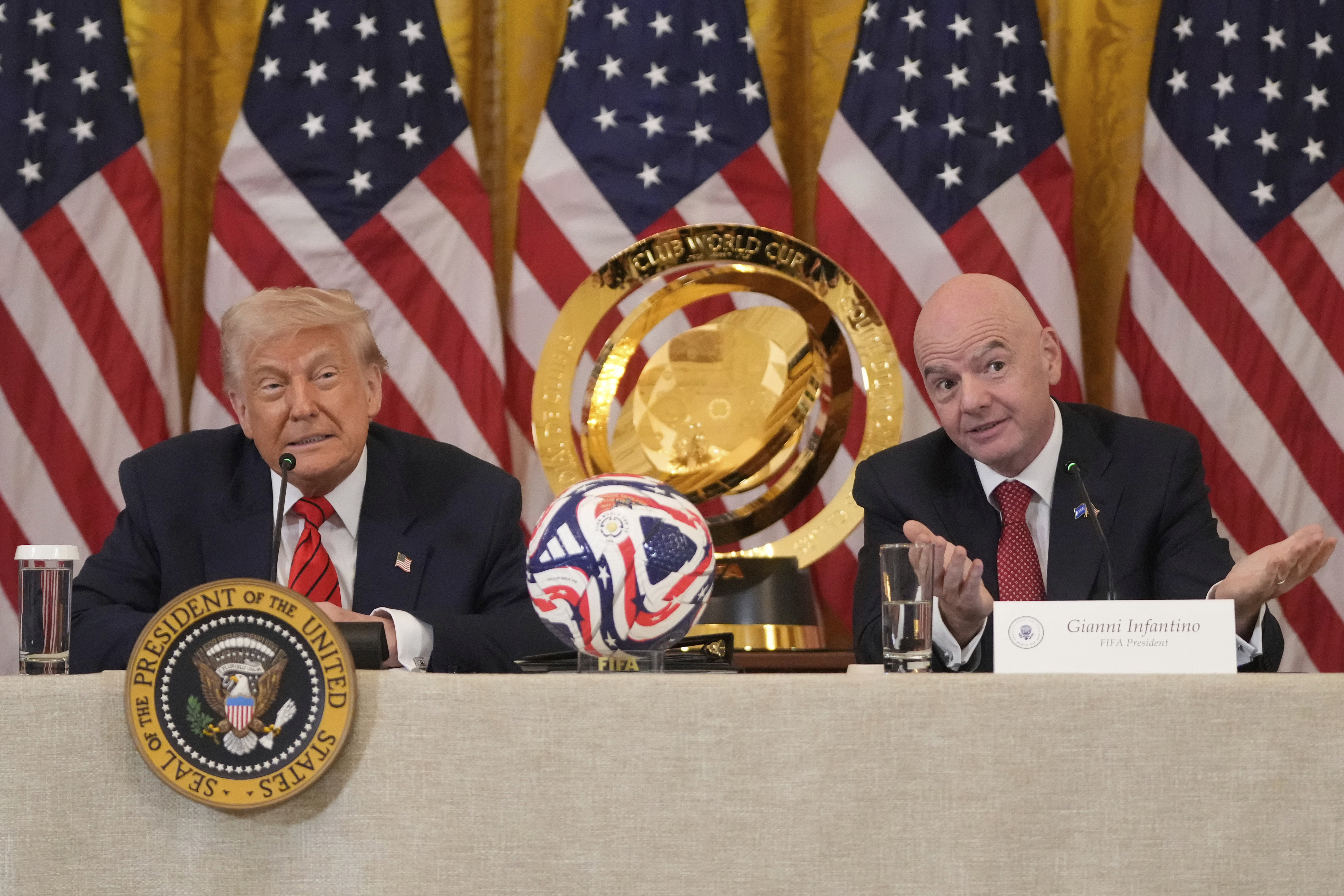 Trump and Gianni Infantino sit at a panel