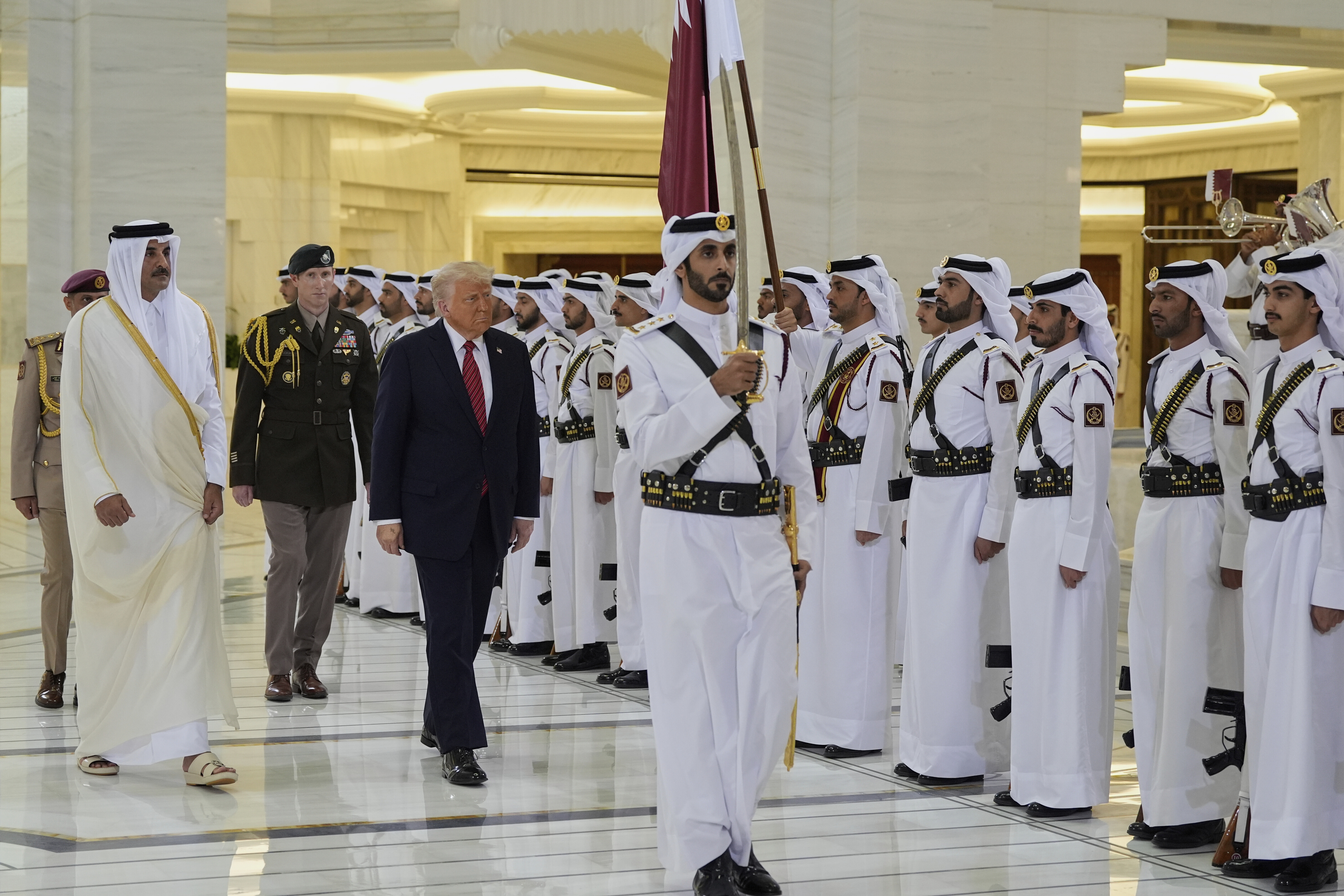 Trump and Emir Sheikh Tamim bin Hamad Al Thani walk past a line of guards