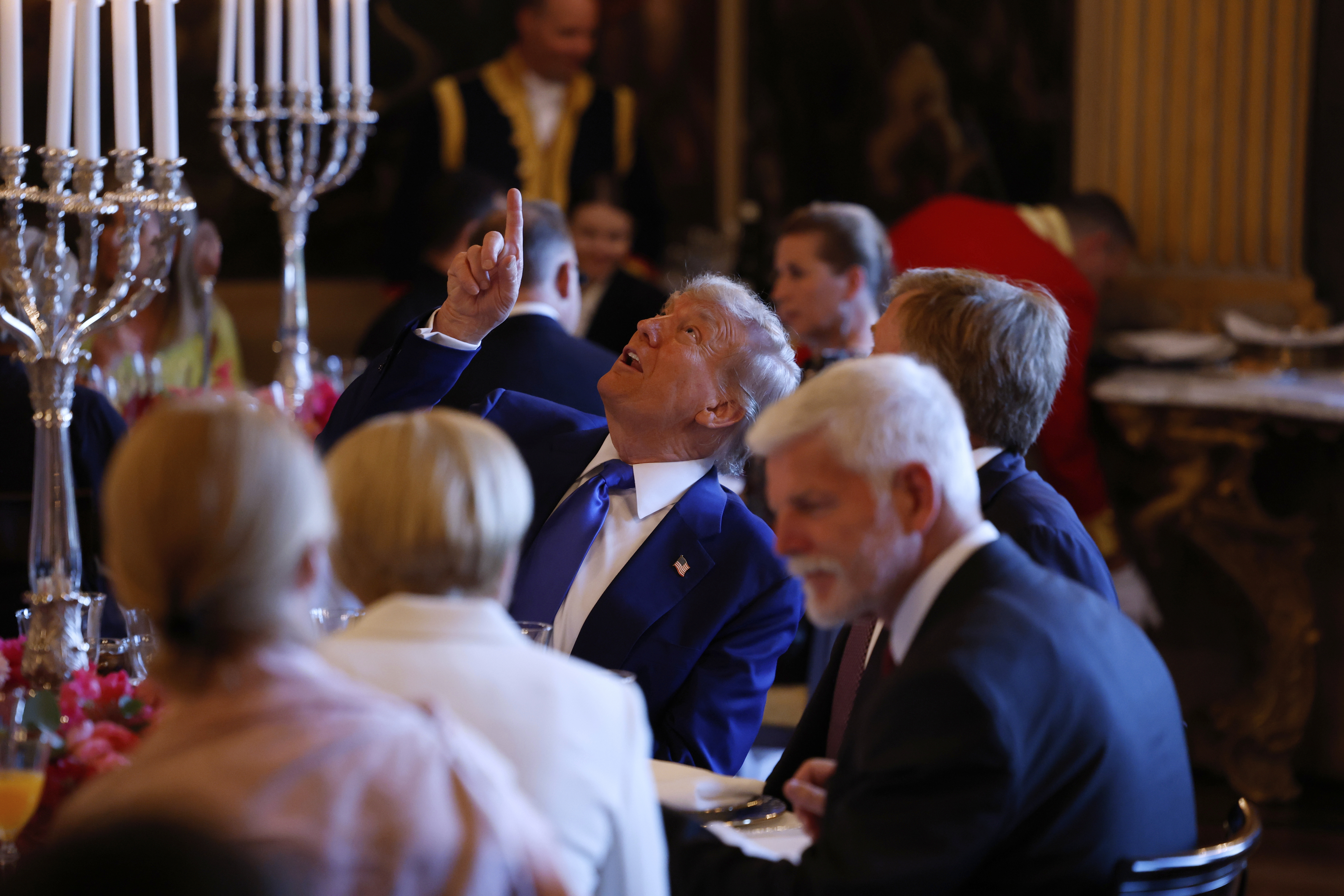 Trump points upwards at a dinner with Netherland's King Willem Alexander