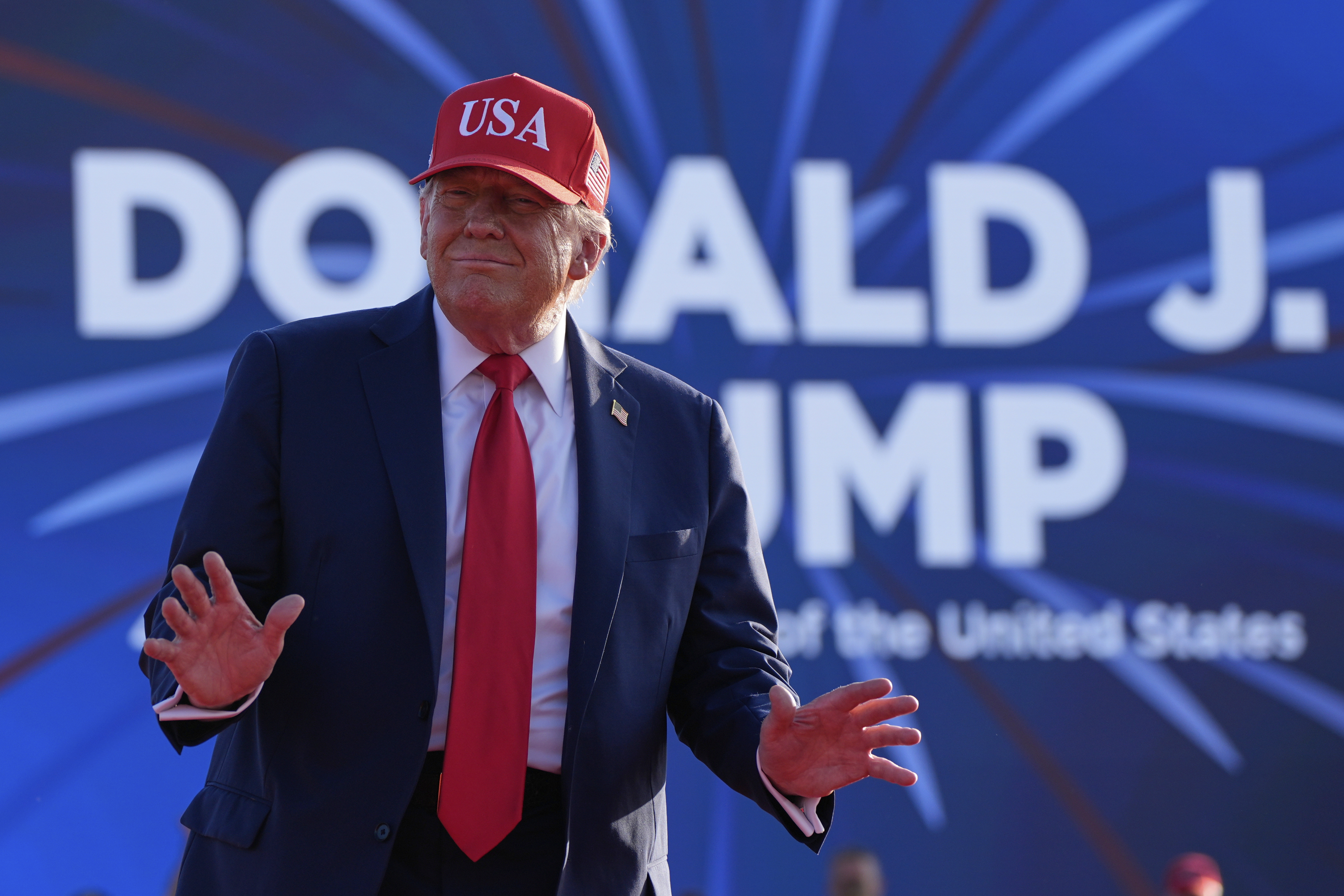 Trump stands in front of a sign with his name in Iowa