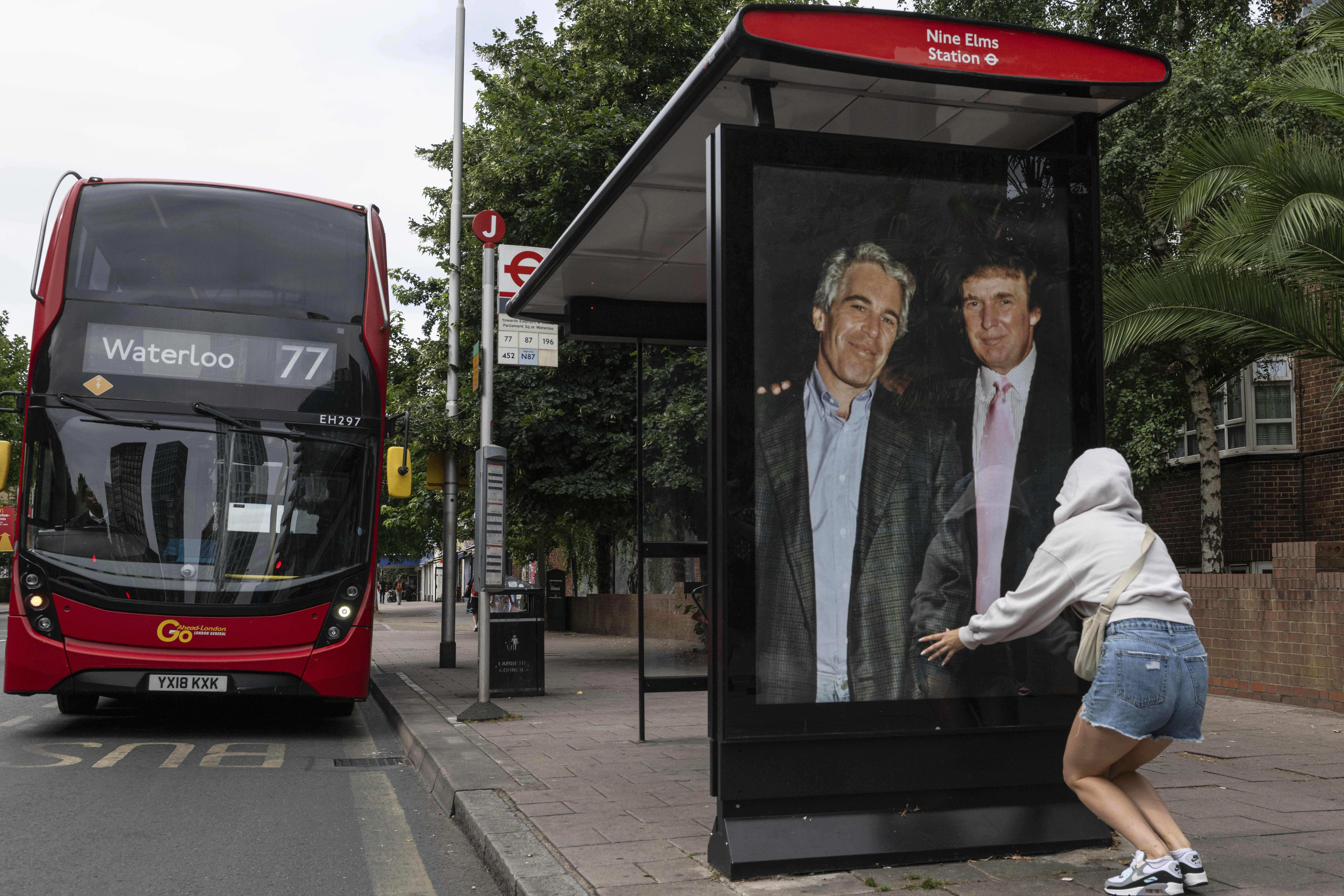 A demonstrator puts a photo of Trump and Epstein up in a London bus shelter.