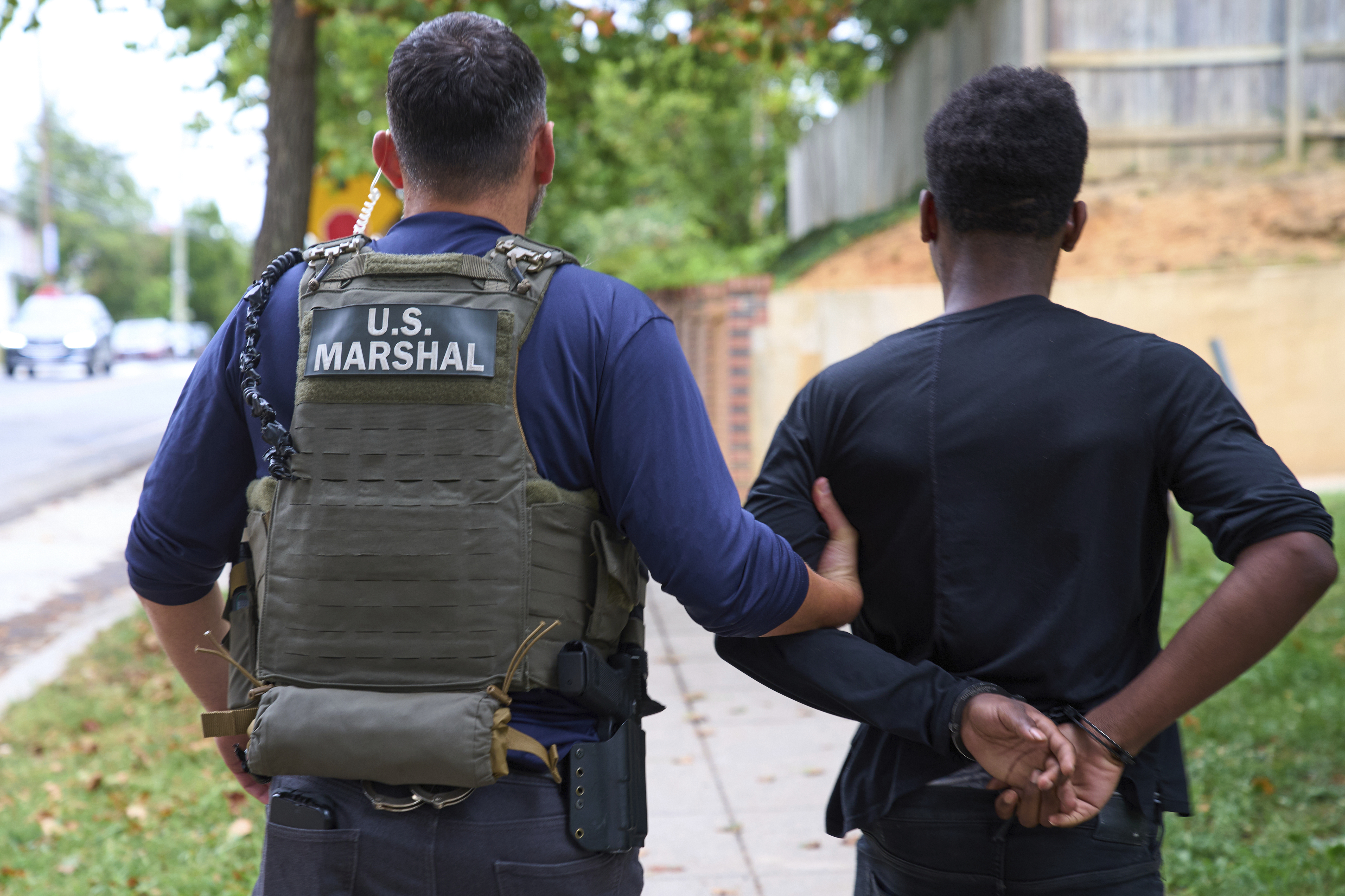A US Marshall leads away a man.