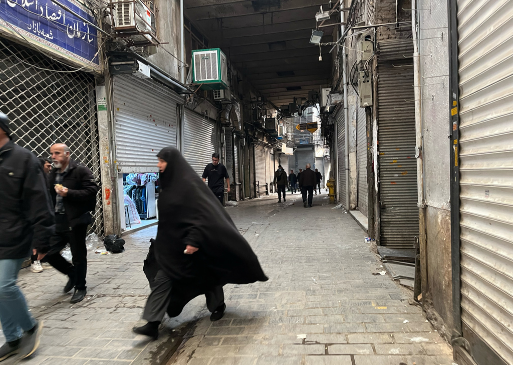 People walk as shops are closed during protests in Tehran's centuries-old main bazaar