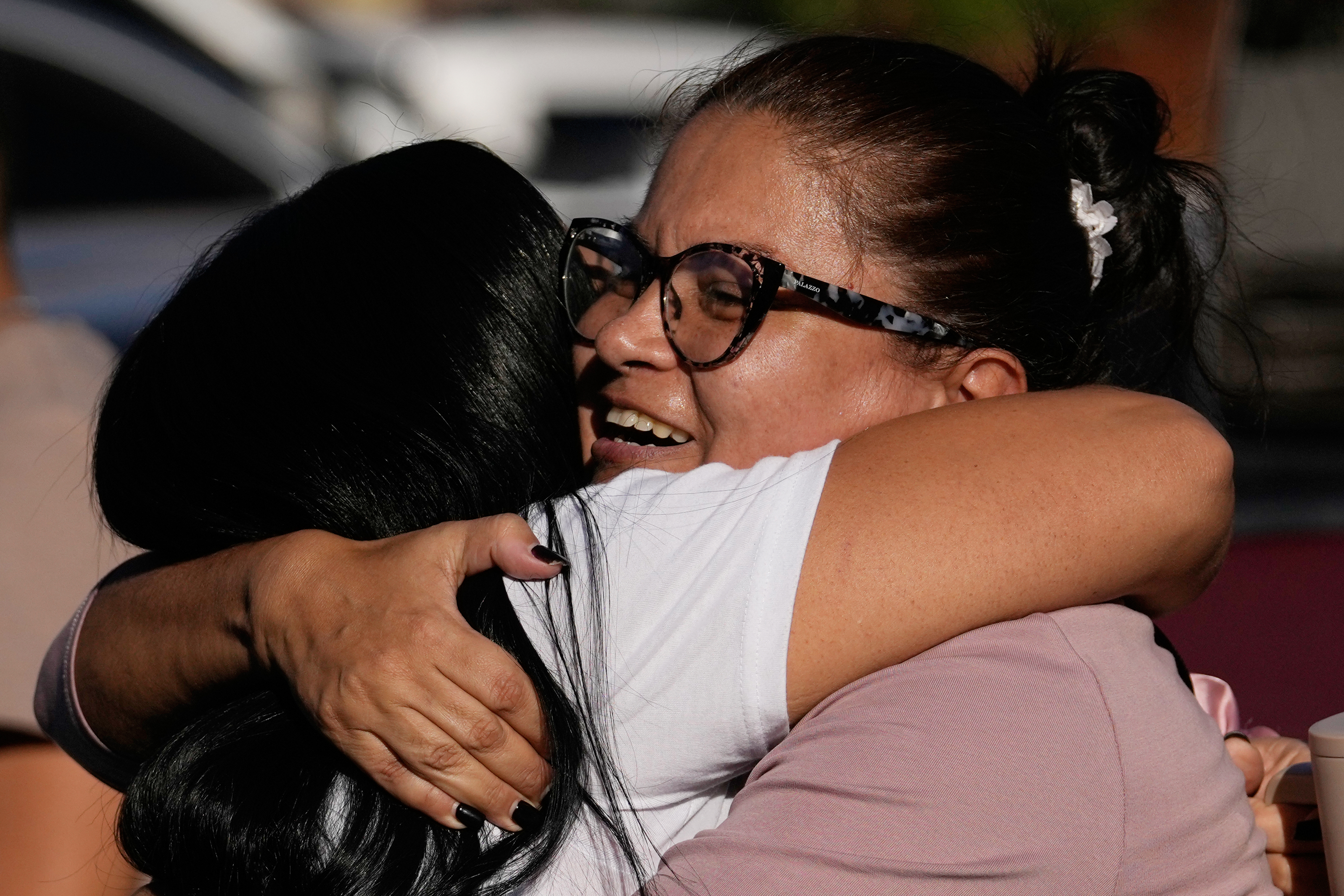 Two women embrace outside a prison.