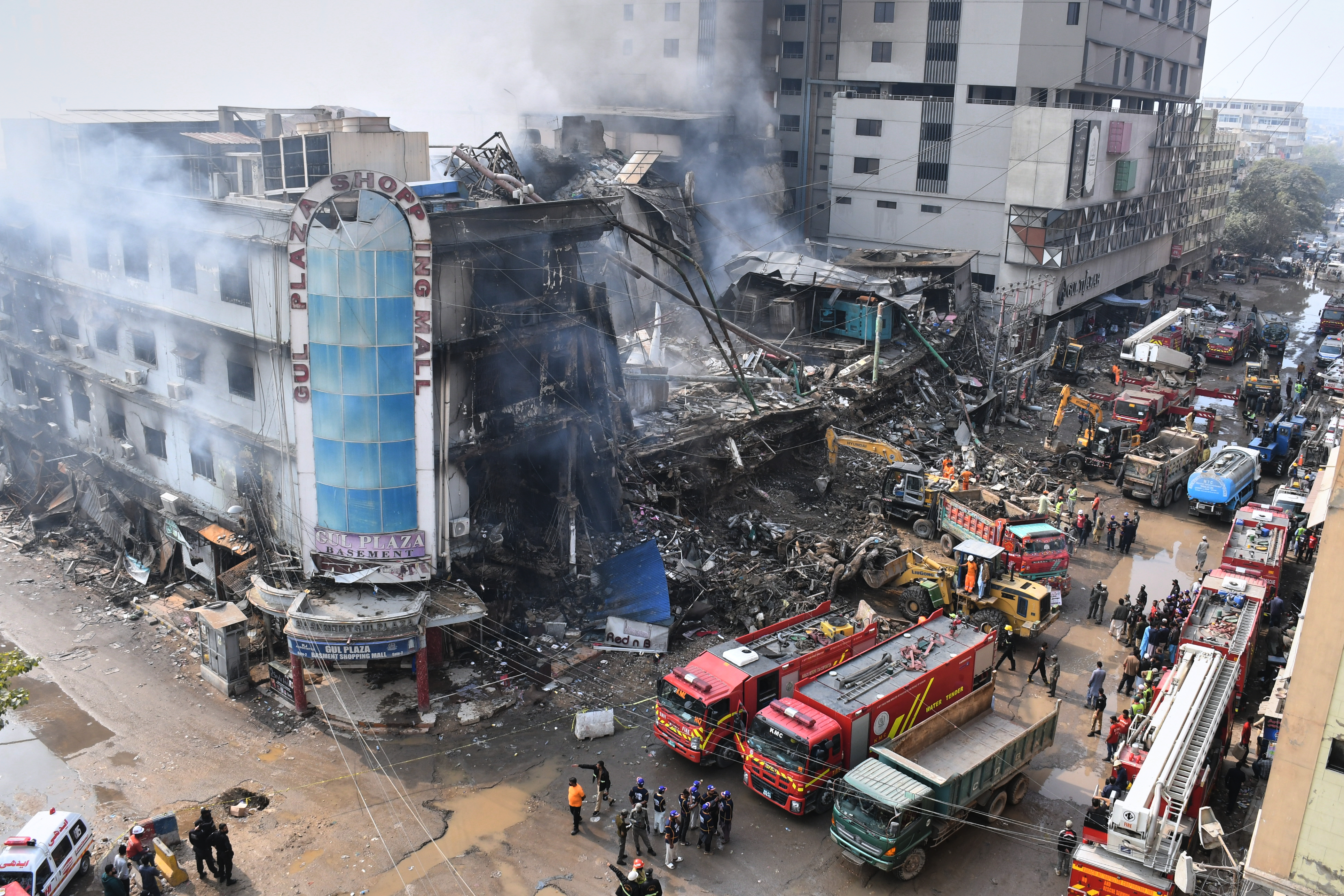 Rescue workers and firefighters work with heavy machinery to search through the rubble of a burnt building of a multistory shopping plaza following a massive fire in Karachi, Pakistan