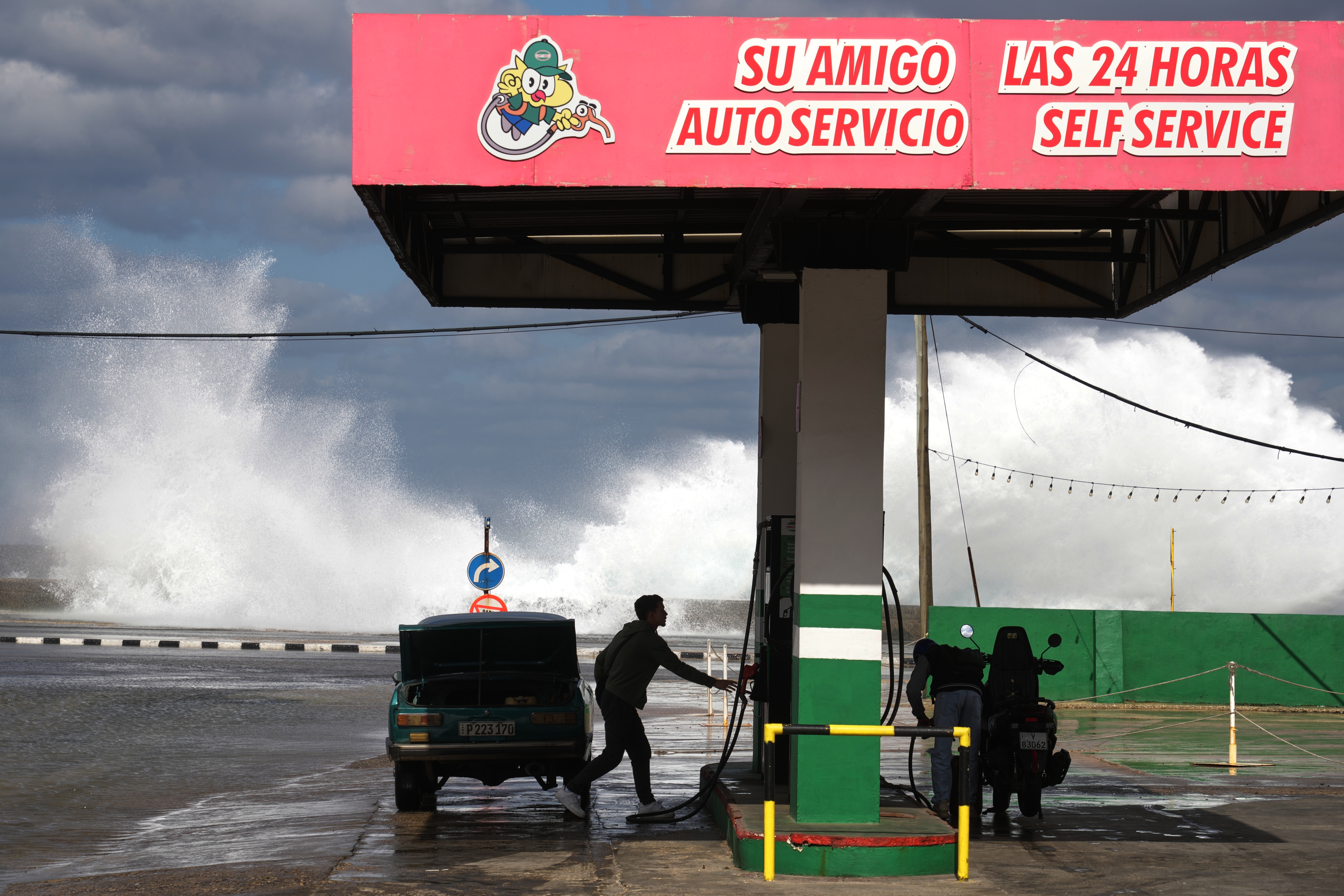 People refuel their car and motorcycle at a gas station near the Malecon in Havana, Cuba