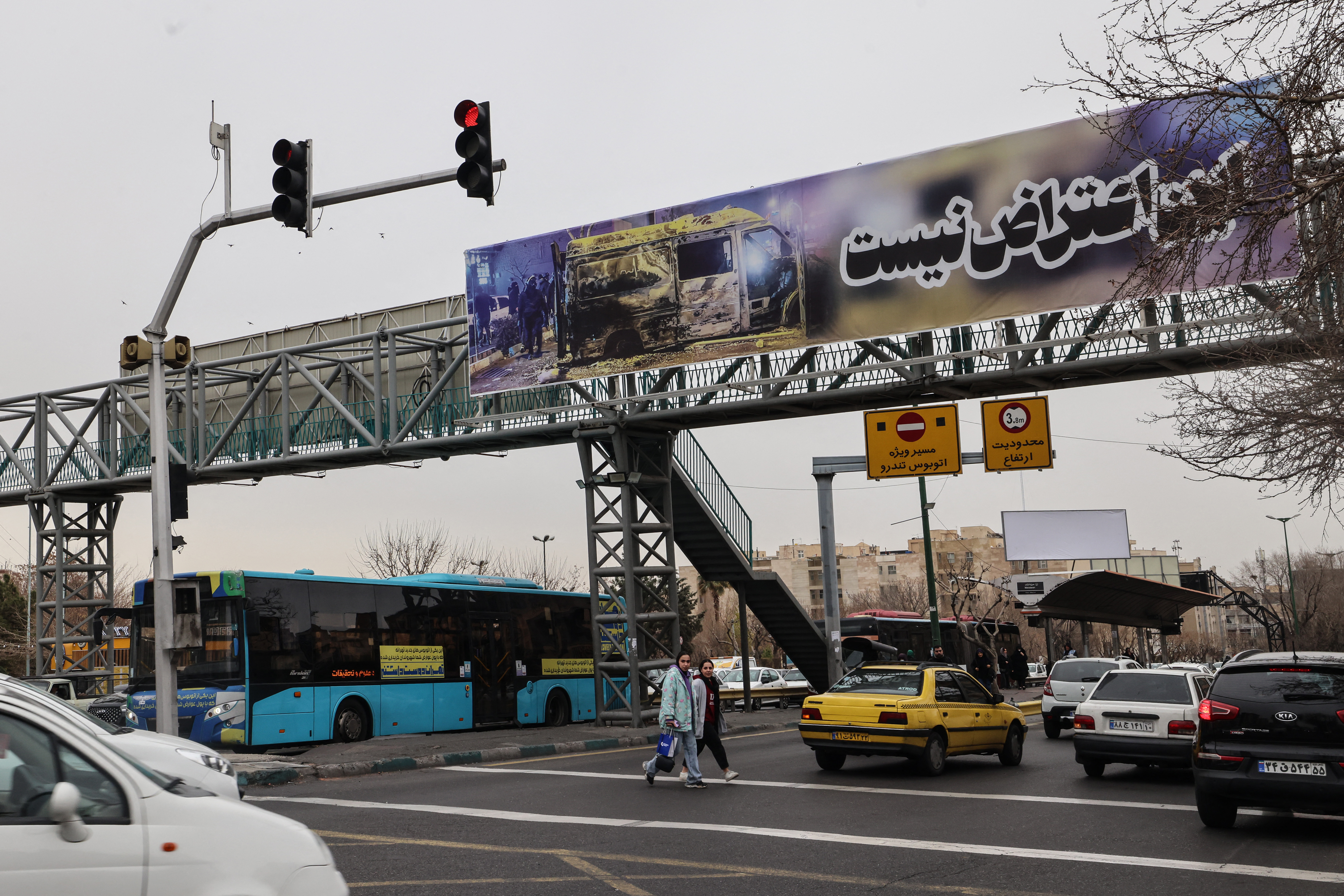 TOPSHOT - Commuters drive under a banner that reads "This is not a protest" in Tehran on January 15, 2026.