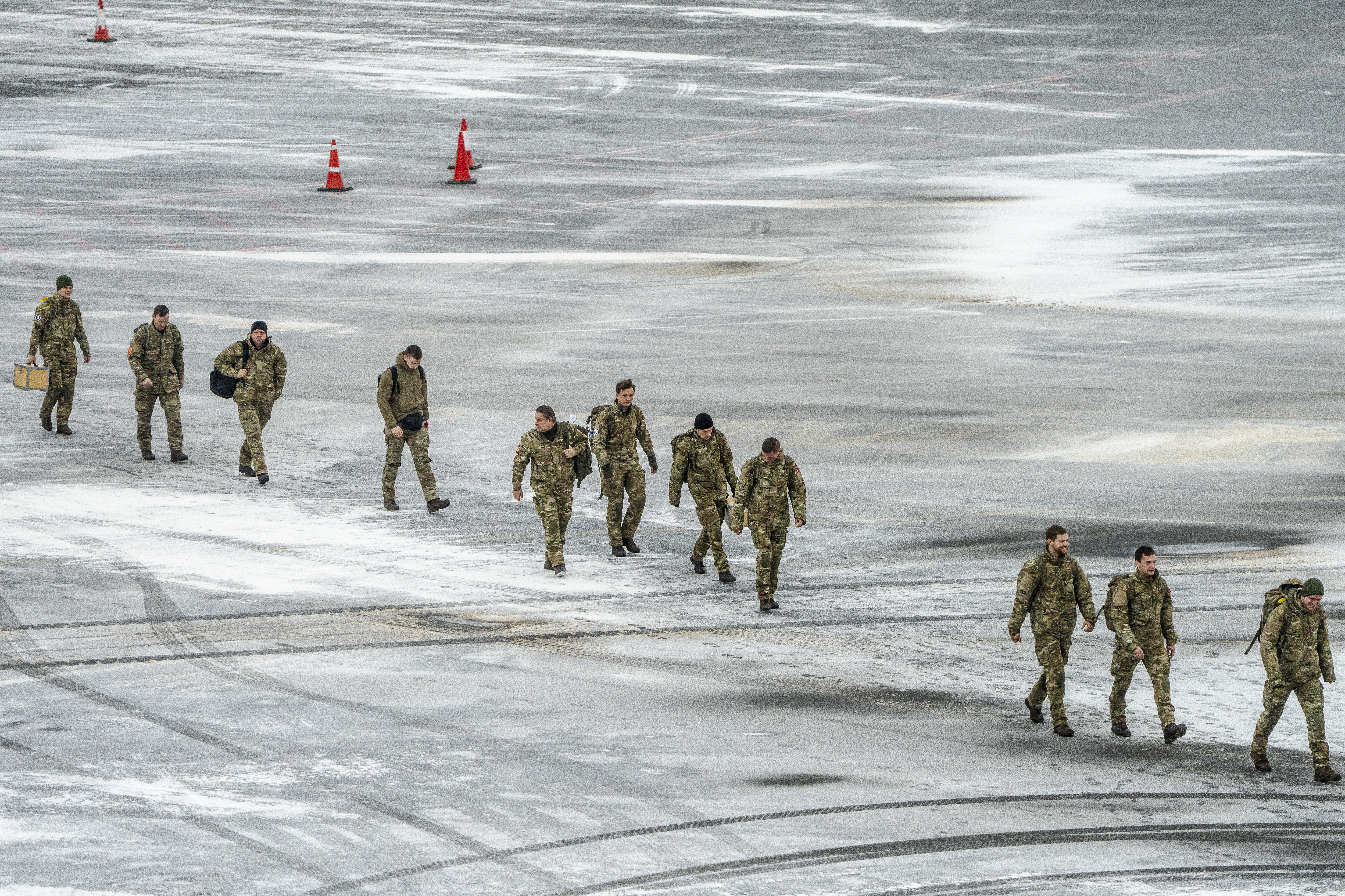Danish soldiers walk across the frozen tarmac after arriving at Nuuk airport, Greenland, on January 19, 2026.