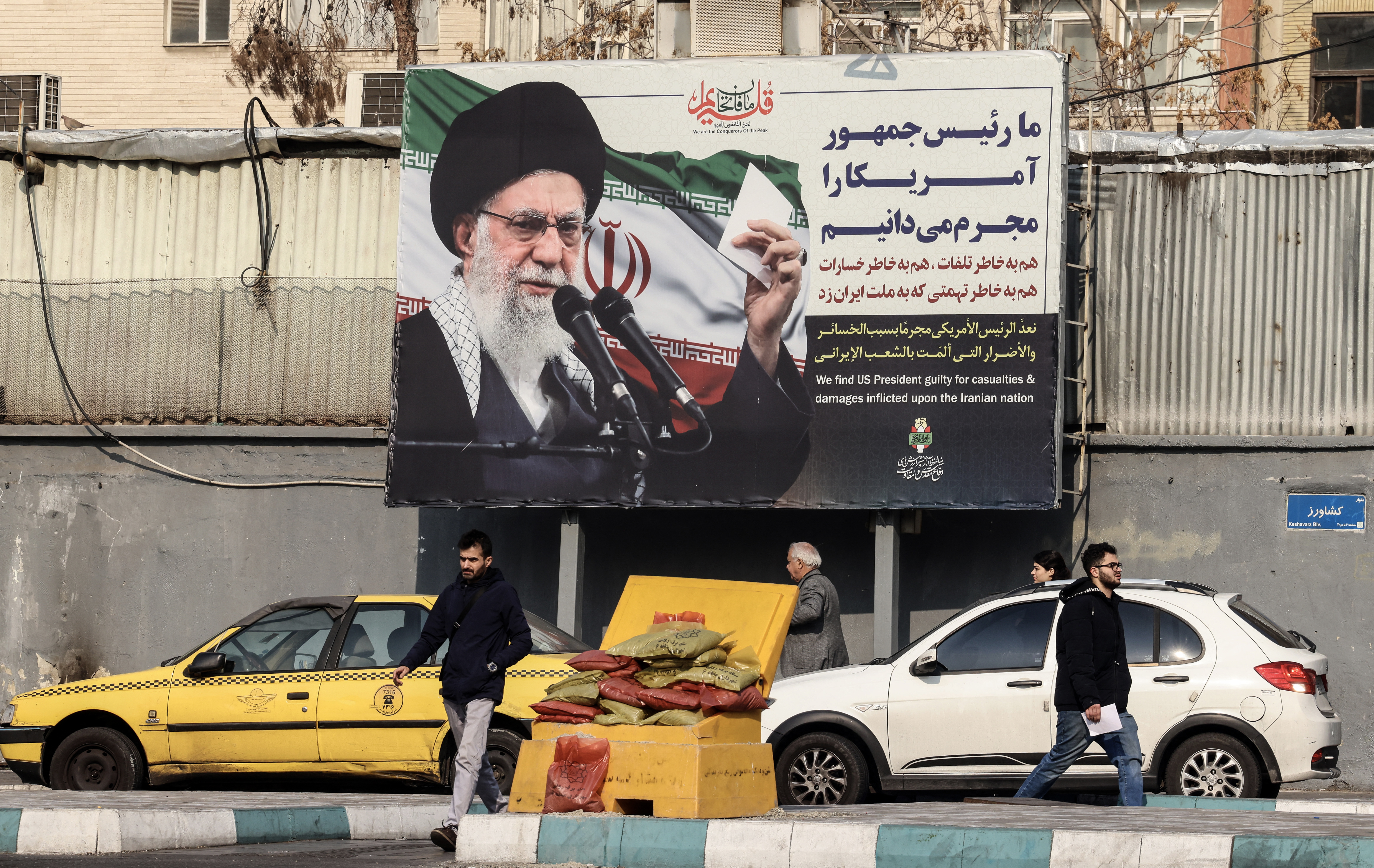 Iranians walk past a billboard showing Iranian supreme leader Ayatollah Ali Khamenei with anti-US rhetoric in Tehran on January 27, 2026.