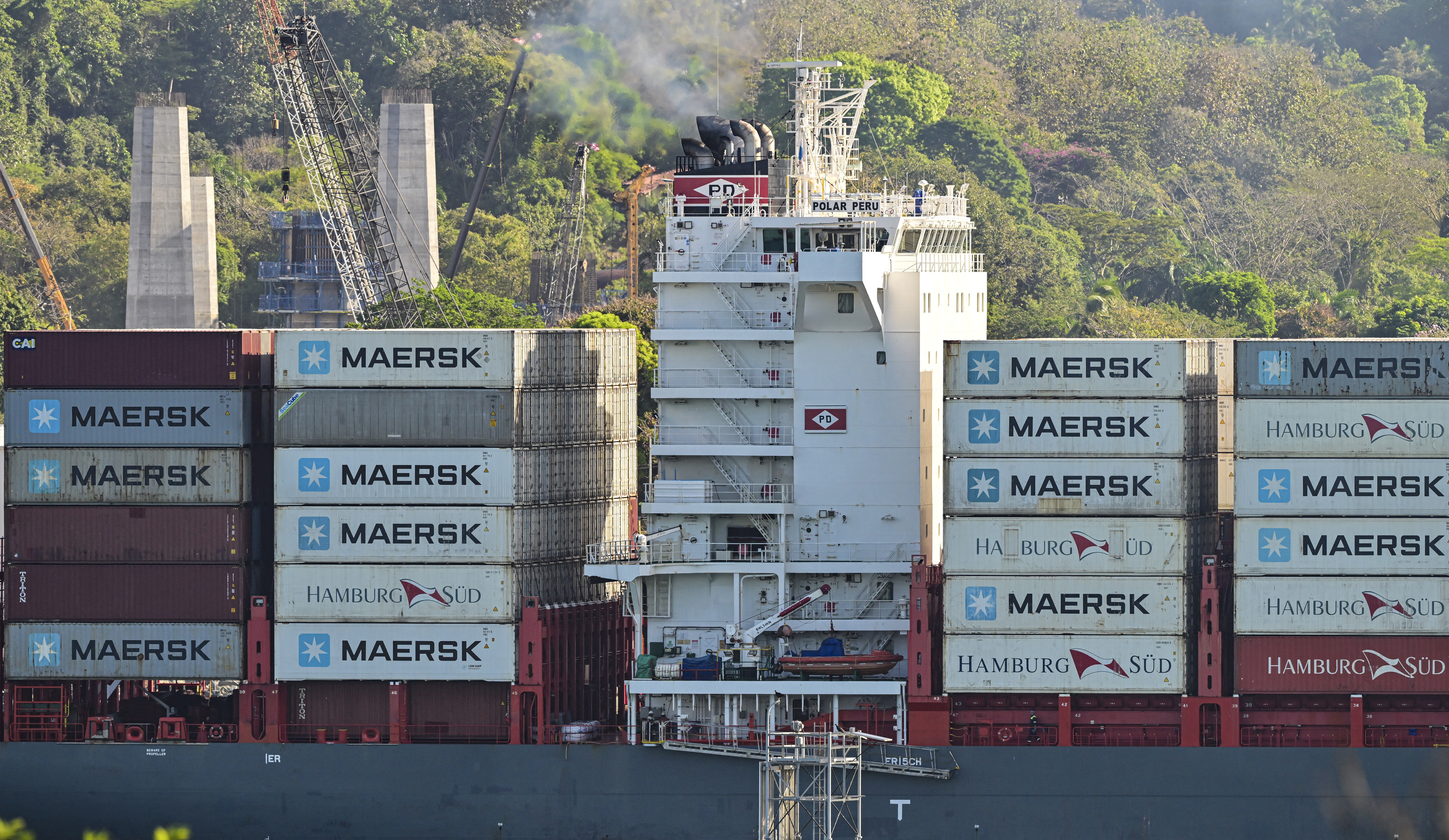 A cargo ship transports containers of the Danish company Maersk at a port.