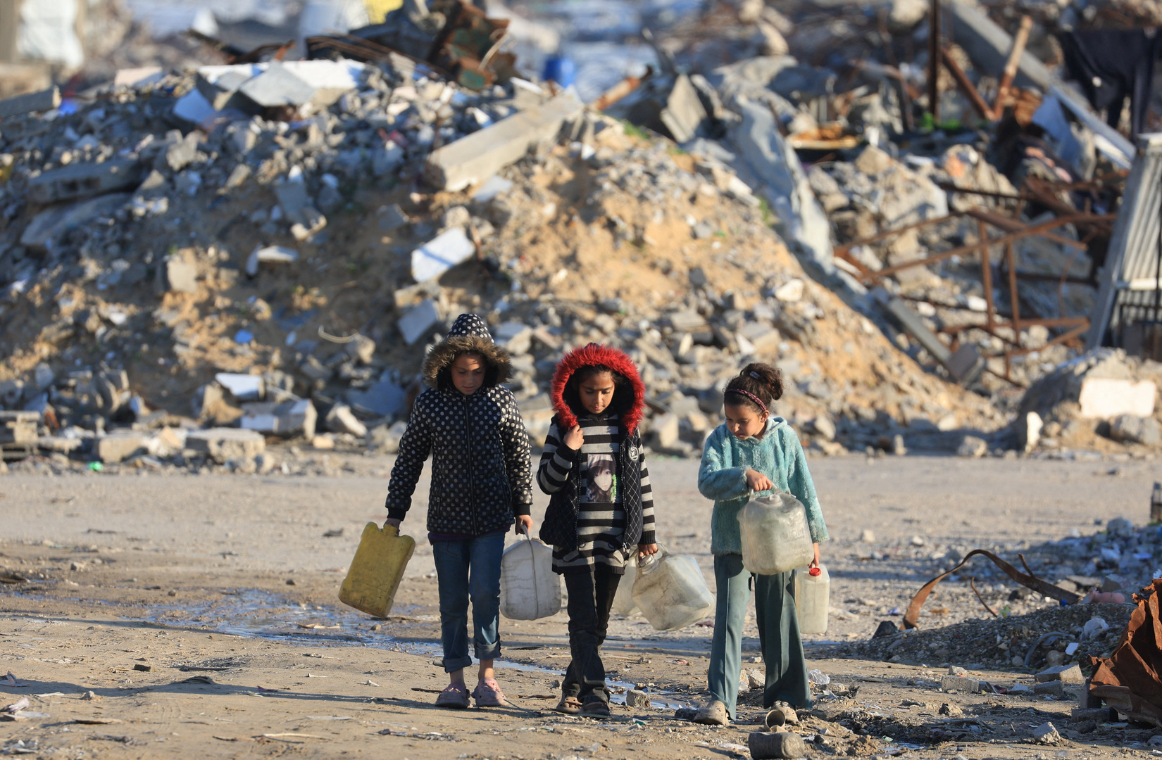 Palestinian girls walk past the rubble of residential buildings destroyed during the war, in Gaza City on Jan. 16, 2026. [Dawoud Abu Alkas/Reuters]