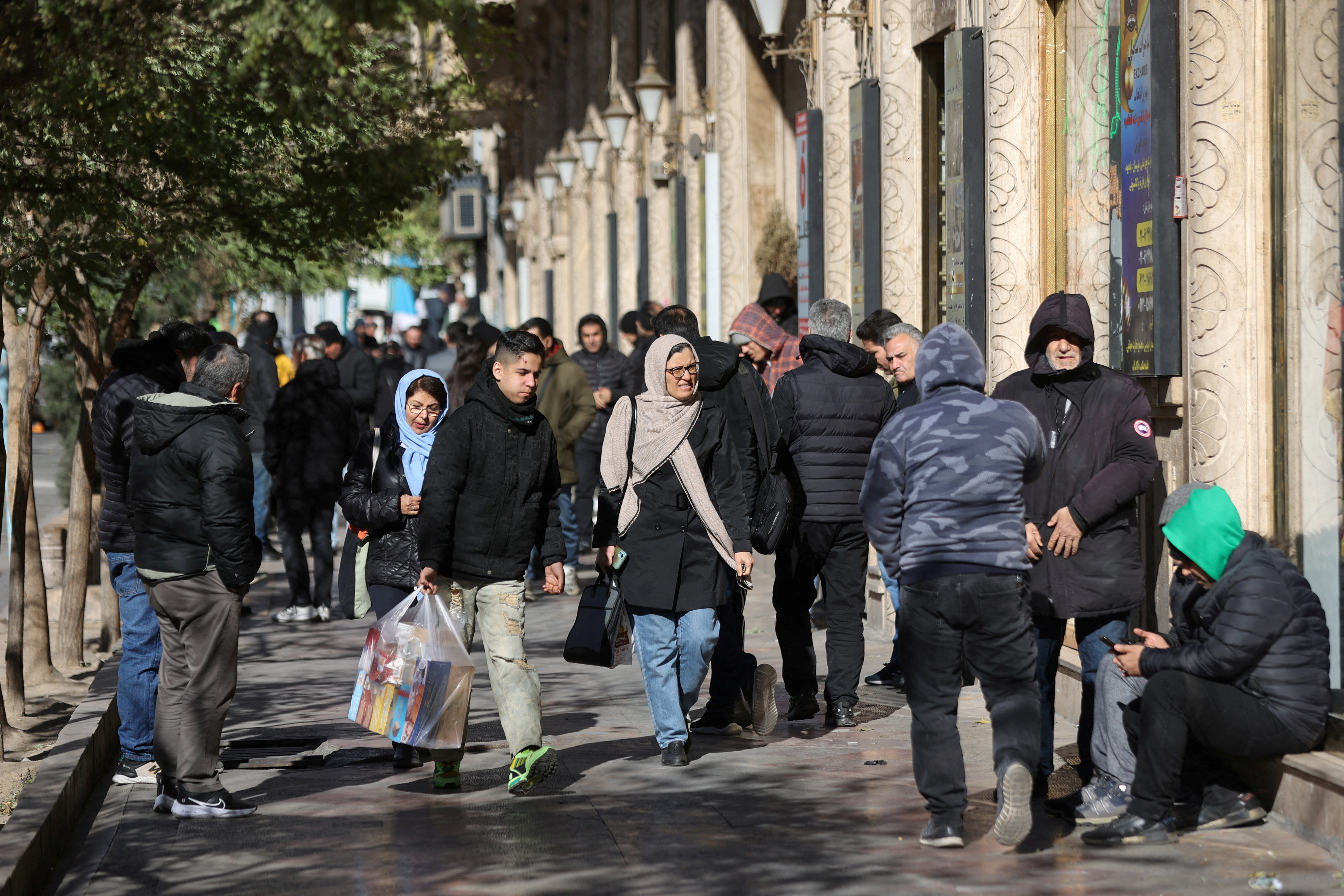 FILE PHOTO: People walk past stores as the value of the Iranian Rial drops, in Tehran, Iran, December 30, 2025. Majid Asgaripour/WANA (West Asia News Agency) via REUTERS ATTENTION EDITORS - THIS PICTURE WAS PROVIDED BY A THIRD PARTY/File Photo