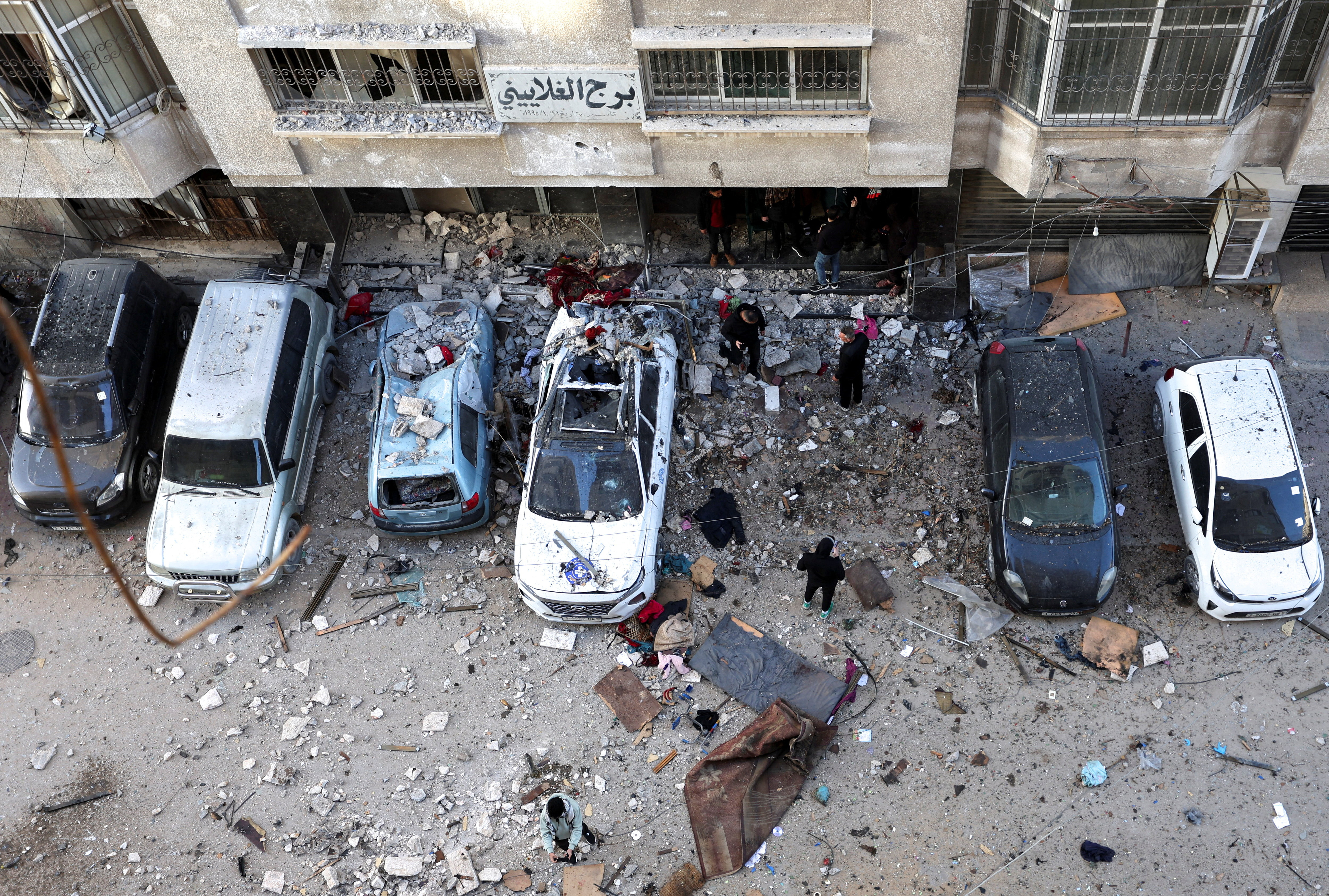 Palestinians inspect the site of an Israeli attack on an apartment building.