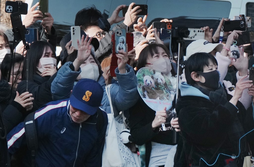 Panda lovers wave goodbye to a truck believed to be carrying the twin pandas upon a departure from Ueno Zoo in Tokyo on January 27, 2026, heading towards their return to China. (Photo by Kazuhiro NOGI / AFP)