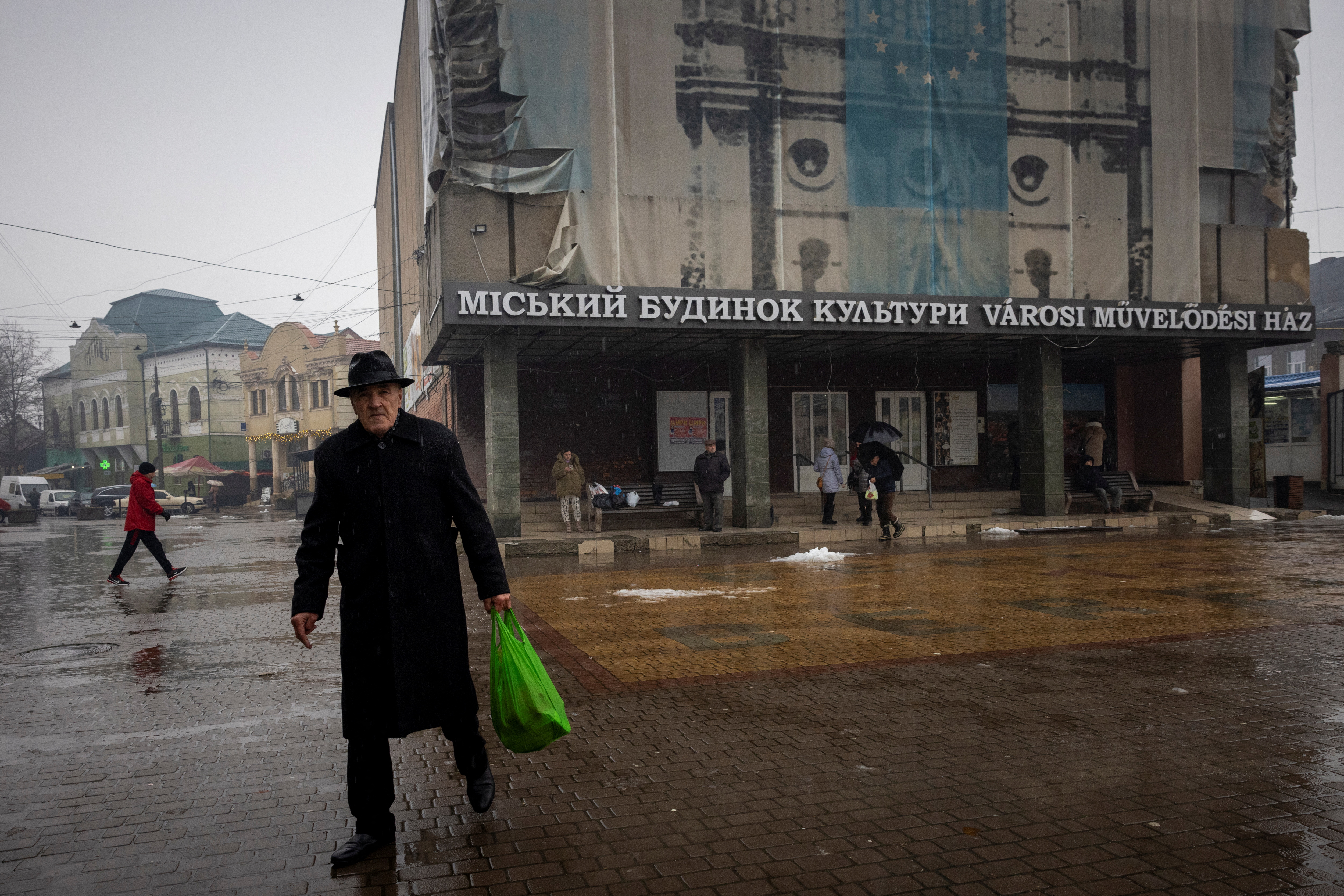 People walk in front of the House of Culture in the town of Berehove, which has a sizeable minority of ethnic Hungarians, amid Russia's attack on Ukraine, in Zakarpattia region, Ukraine December 1, 2023. REUTERS/Thomas Peter