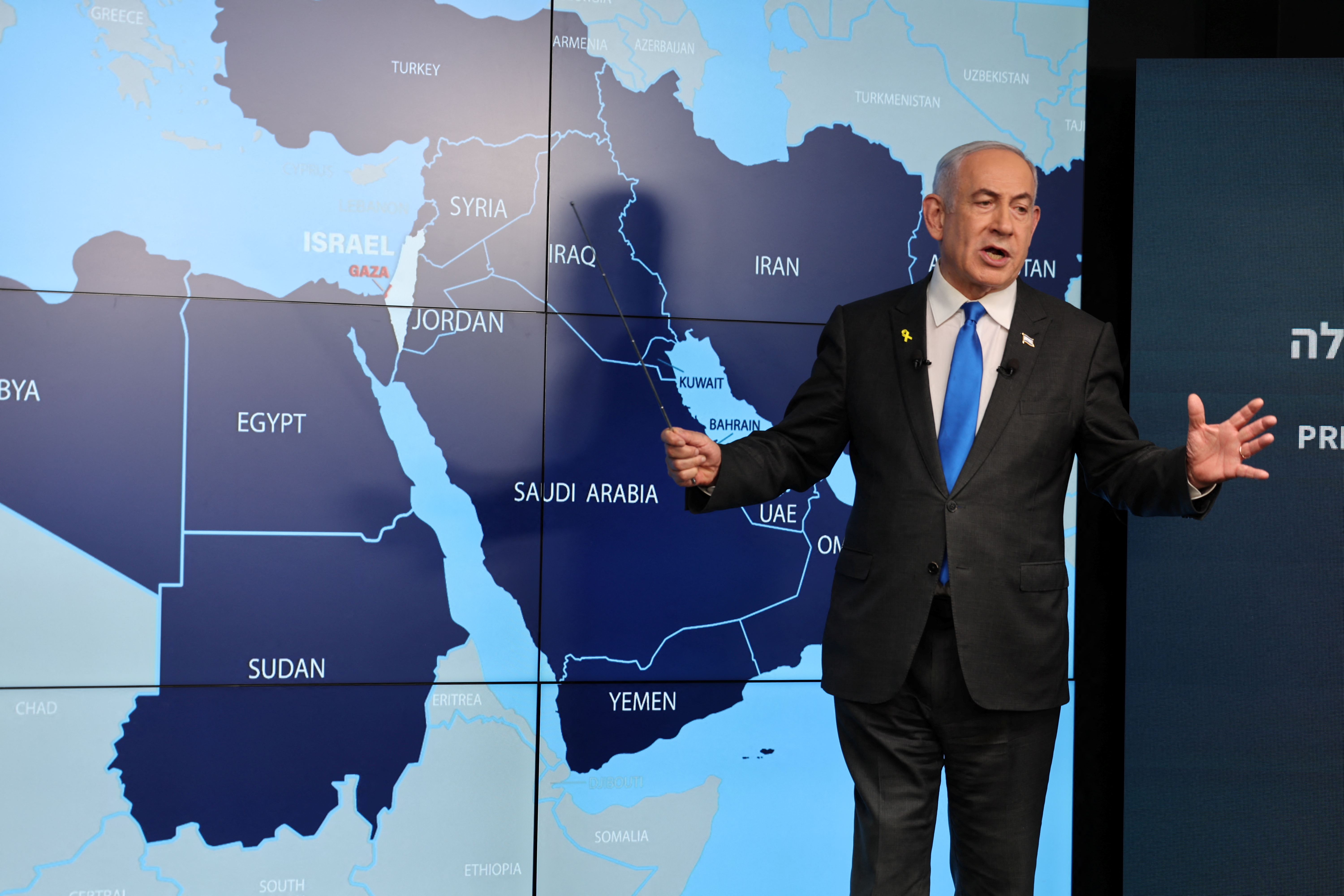 Netanyahu stands in front of a map of the Middle East