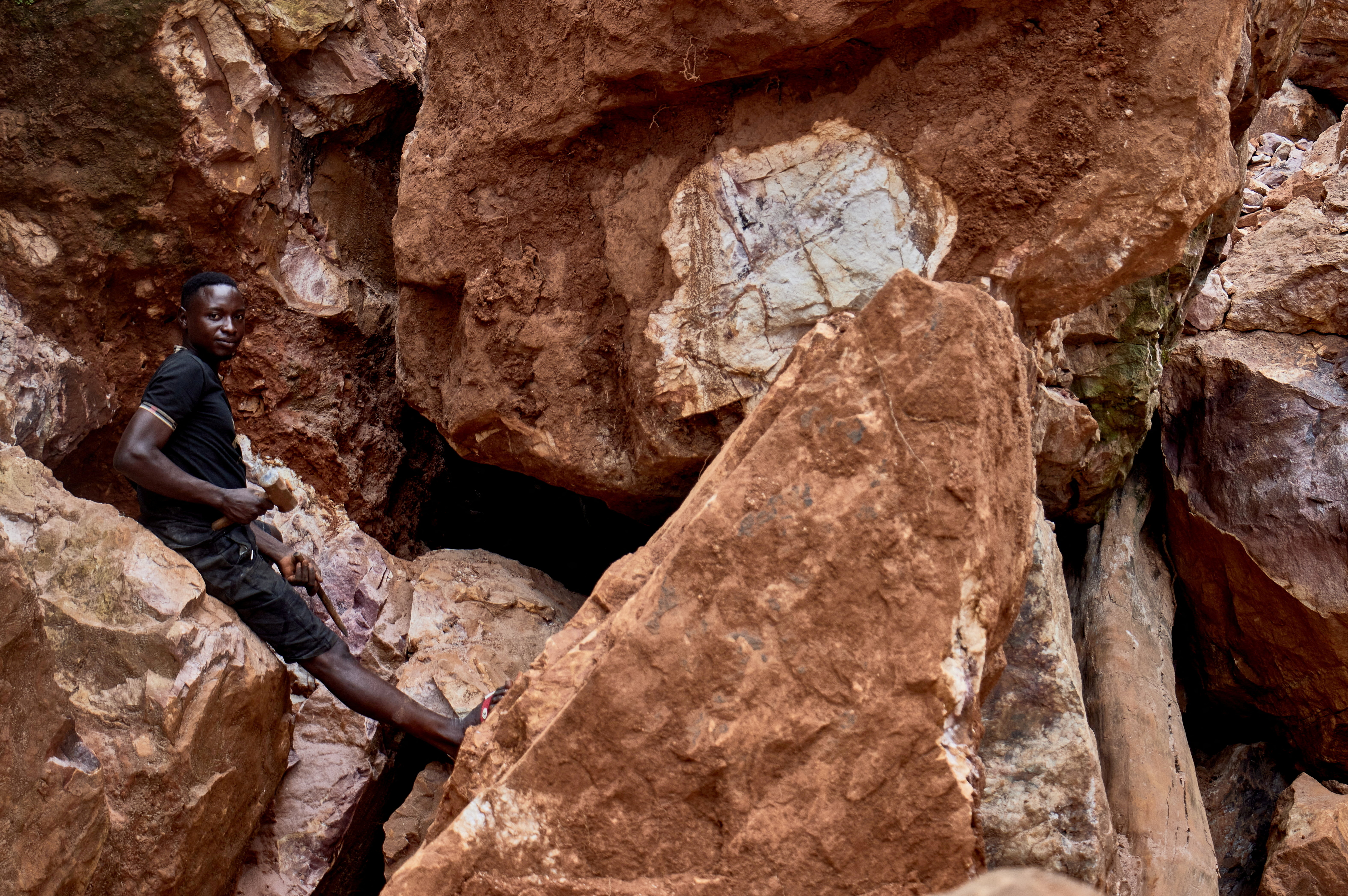 An artisanal miner rests while digging in an open-pit mine.
