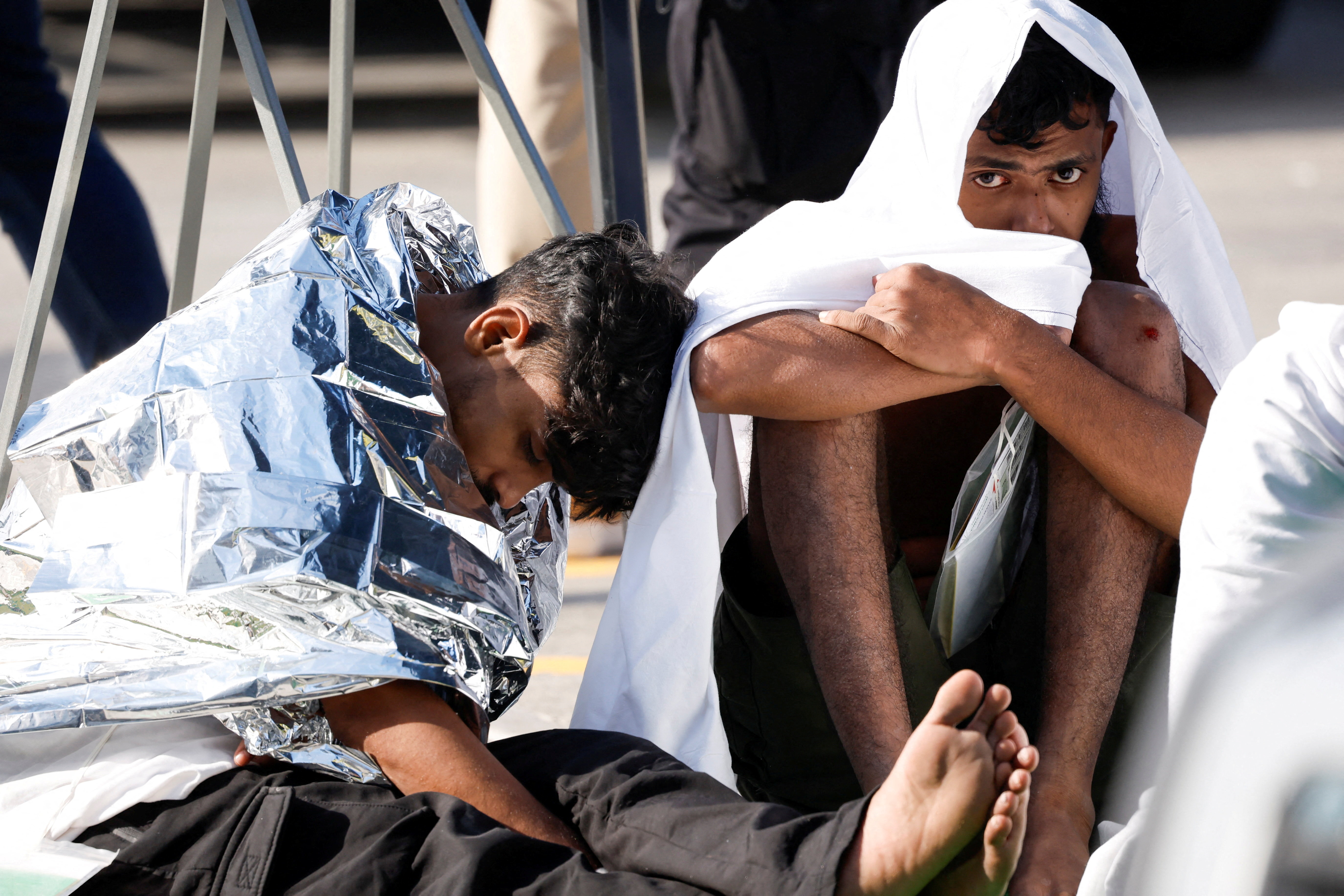 Migrants sit on the ground after a group of some 60 migrants was brought to Malta after their boat capsized close to the Mediterranean island, in Bugibba, Malta, December 12, 2025. REUTERS/Darrin Zammit Lupi TPX IMAGES OF THE DAY
