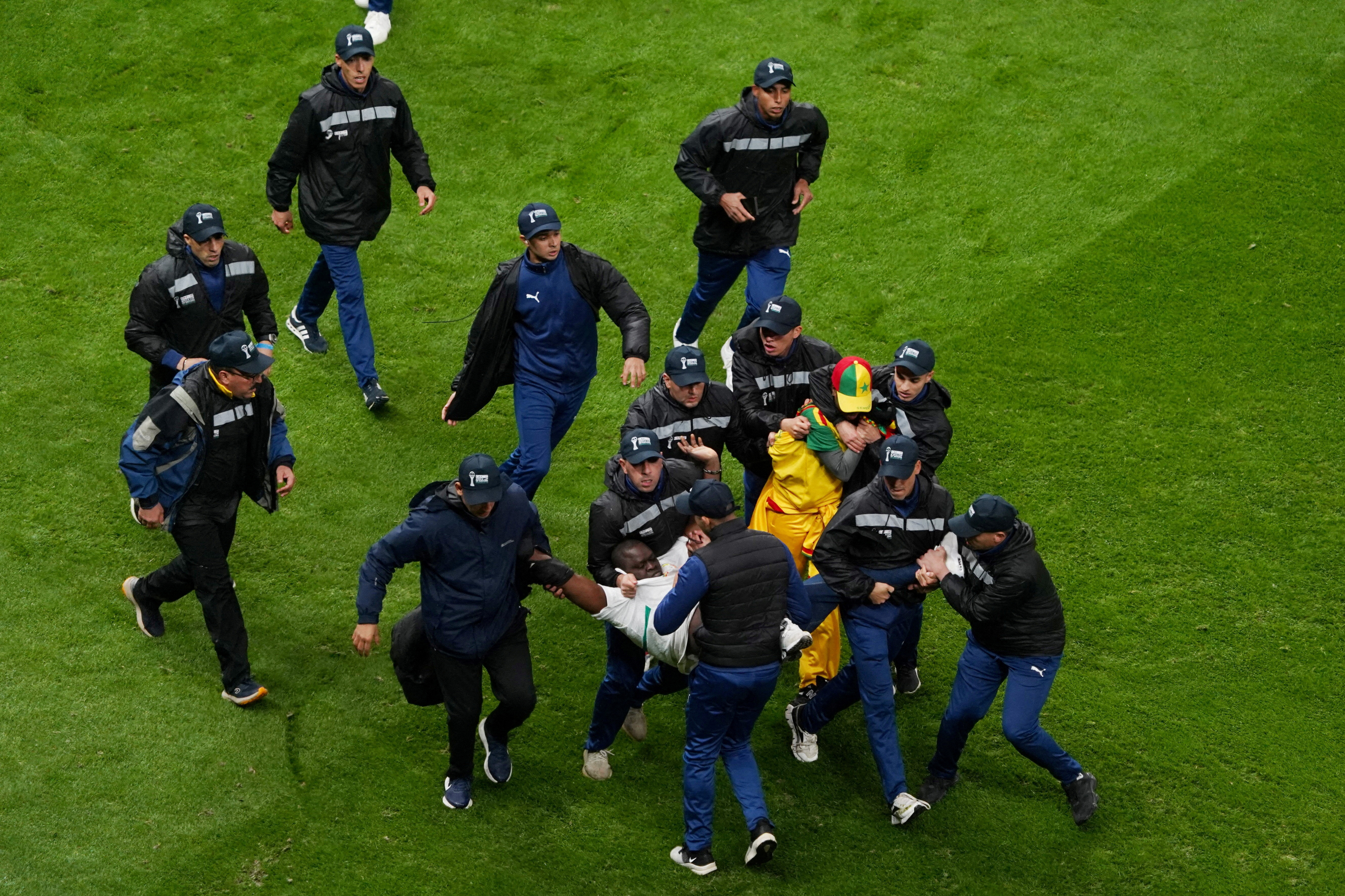 Security staff tackle Senegal fans who invaded the pitch.