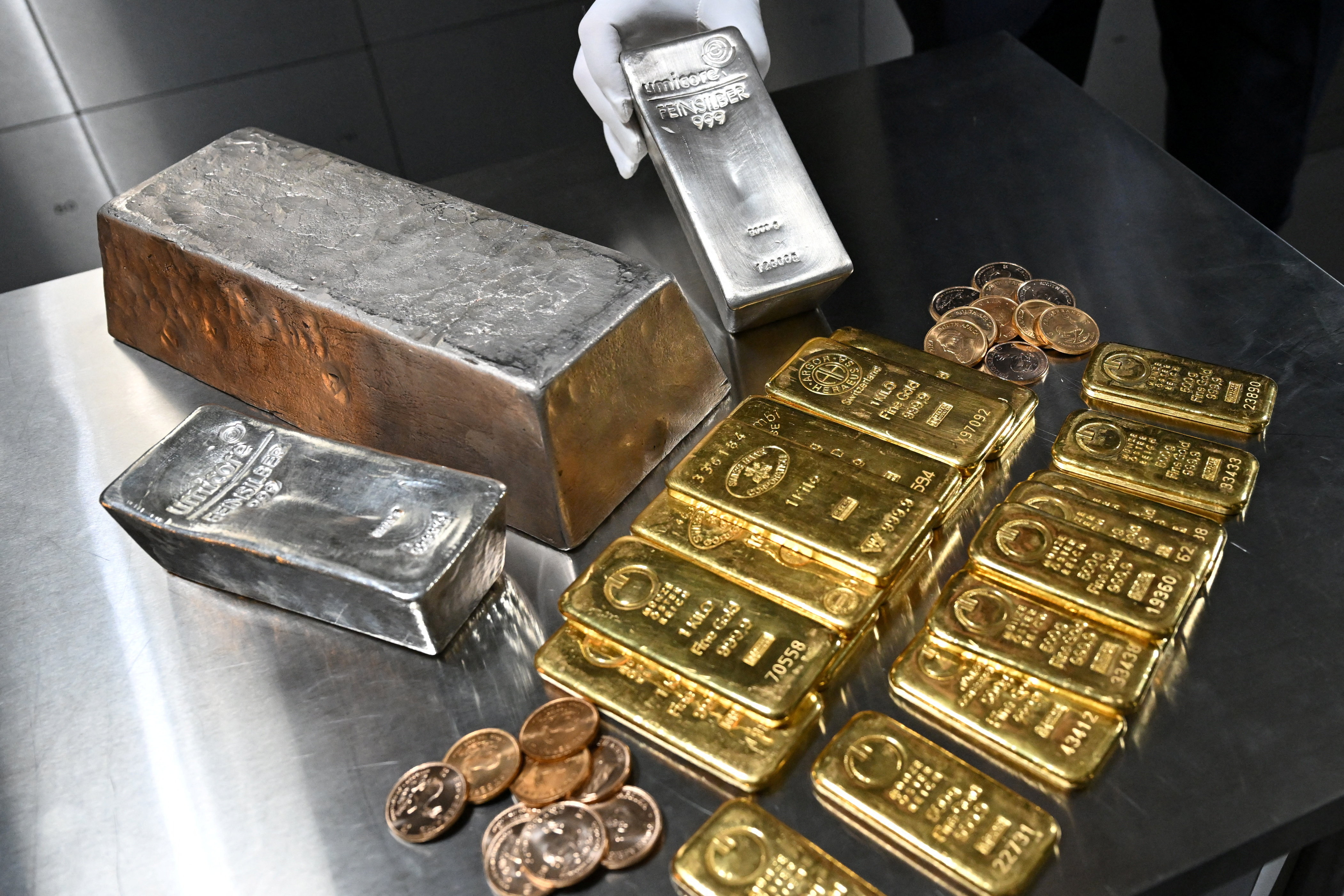 An employee shows a silver bar, as gold and silver bars of various values are stored.