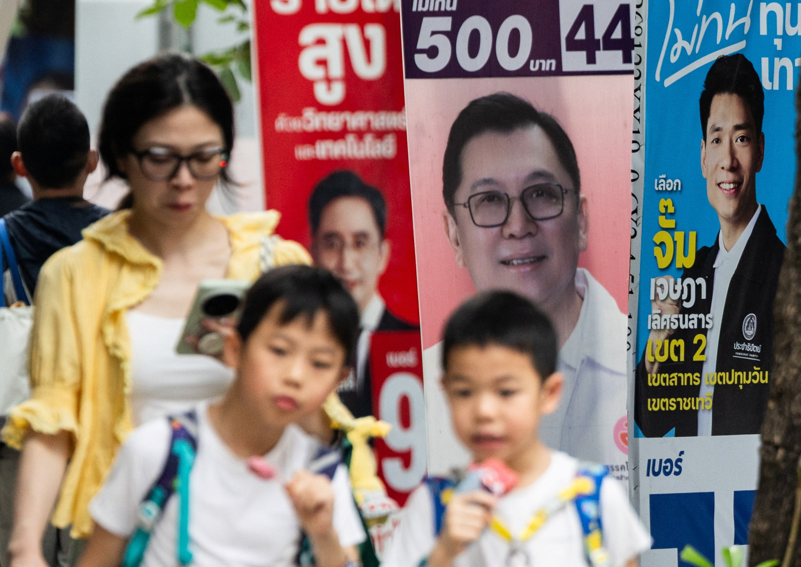 People walk next to electoral campaign posters, before Thailand general elections on February 8, in Bangkok, Thailand, February 4, 2026.
