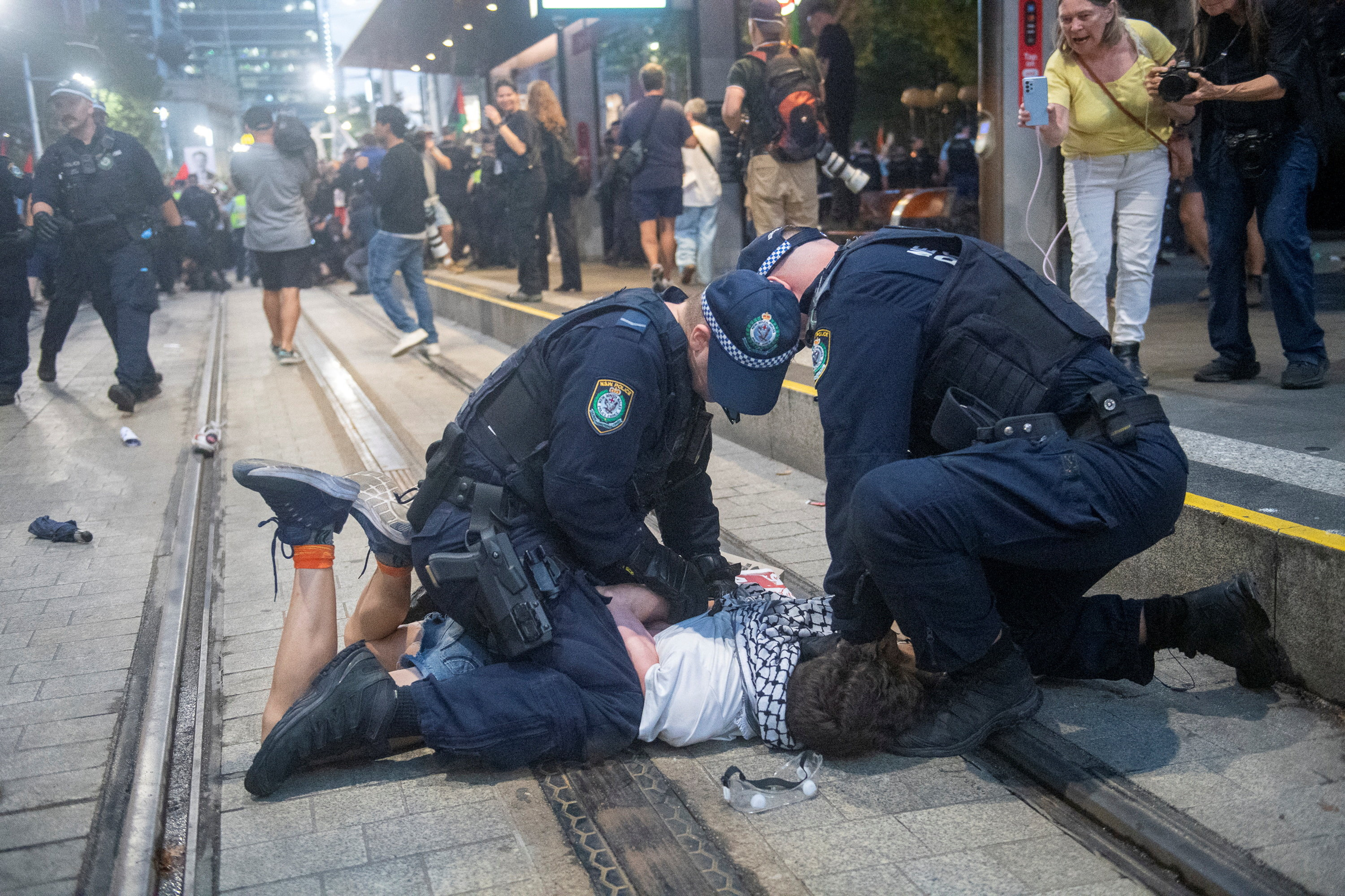 Police officers detain a protester forced onto the ground.