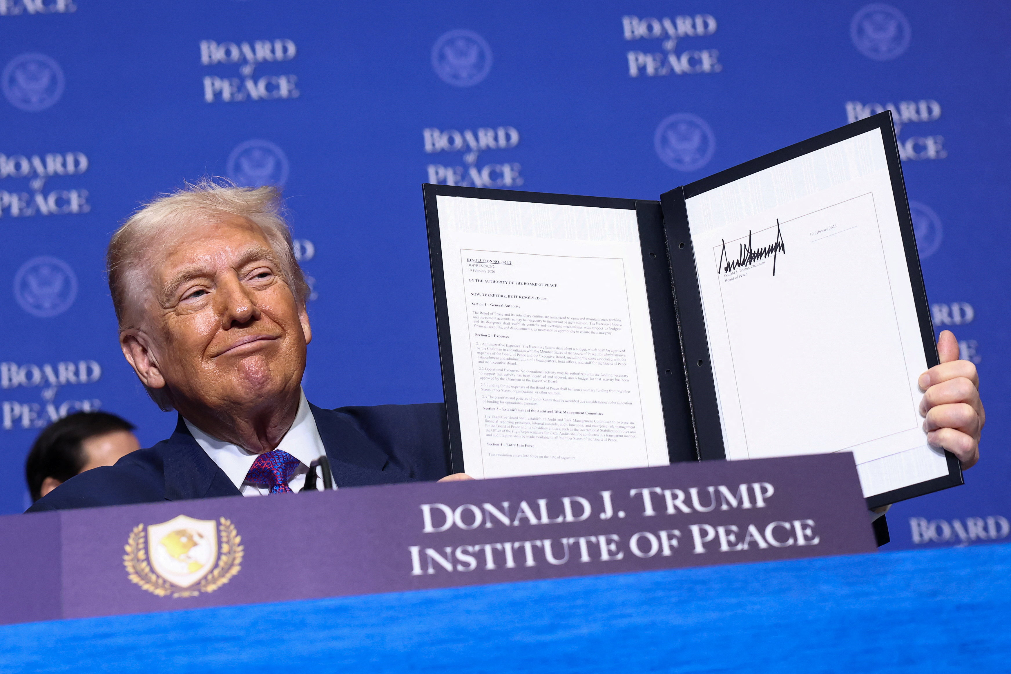 US President Donald Trump holds up a signed document at the Board of Peace meeting.