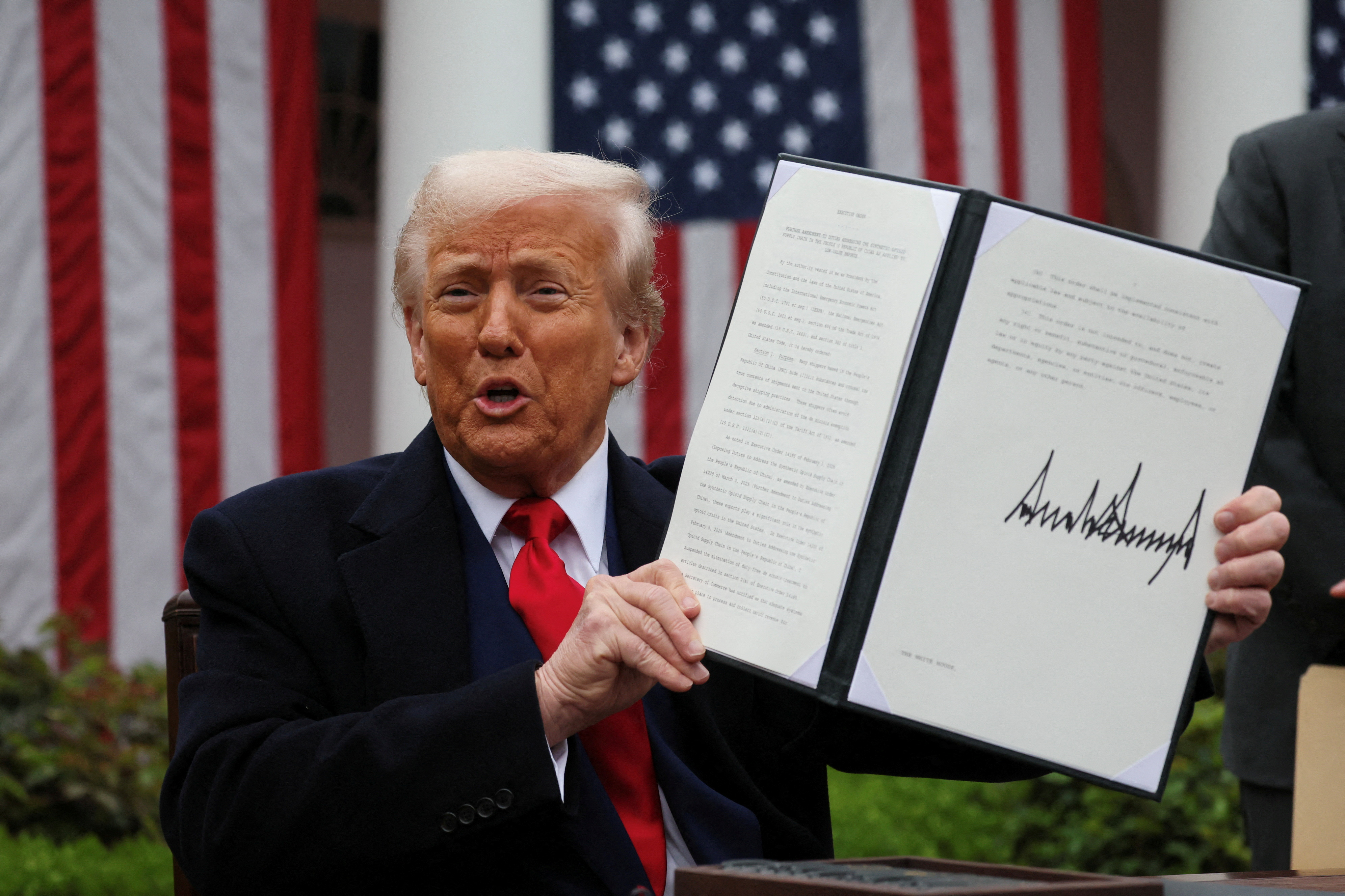 Donald Trump holds up a signed executive order on tariffs