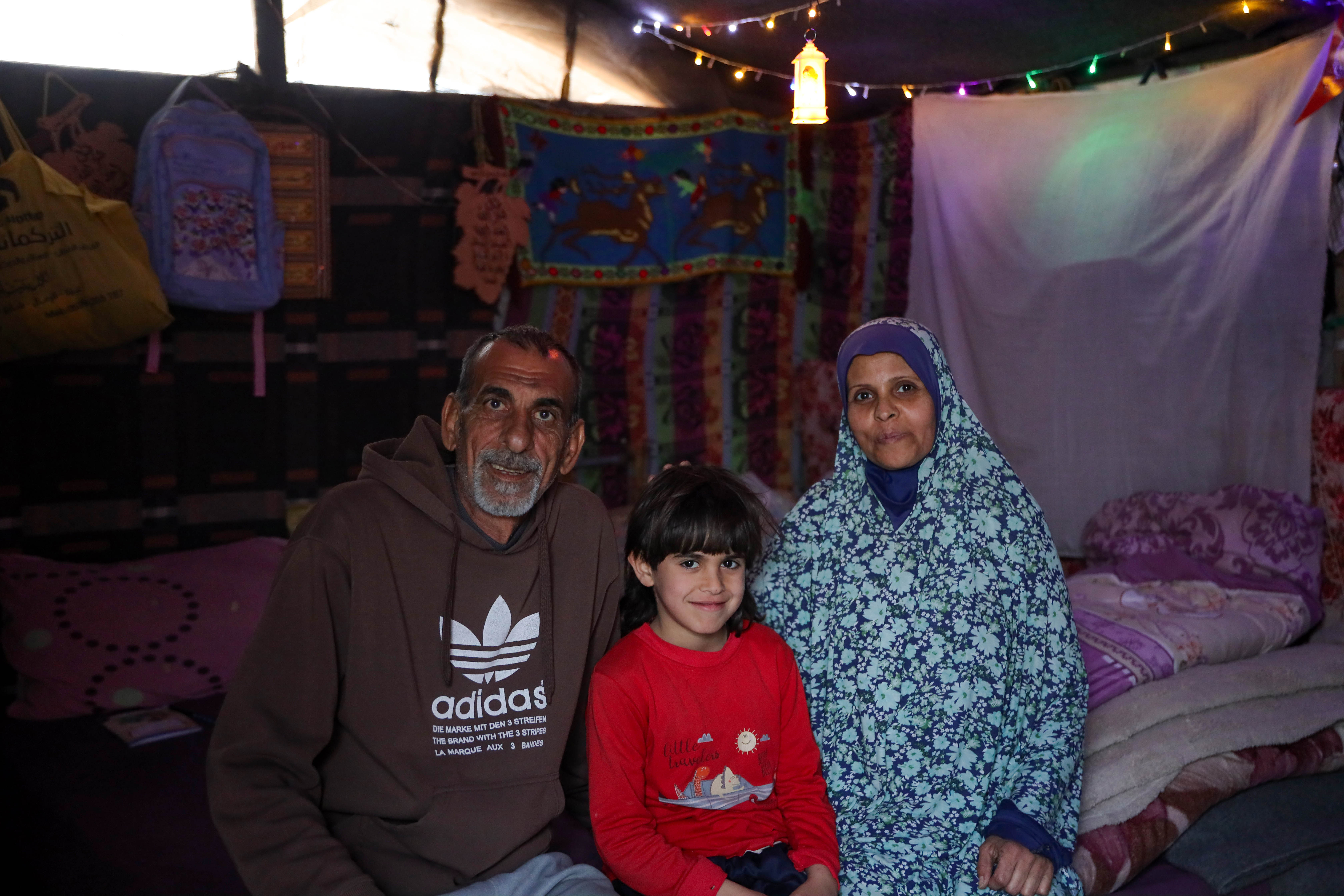 A husband and wife with their son in a decorated tent