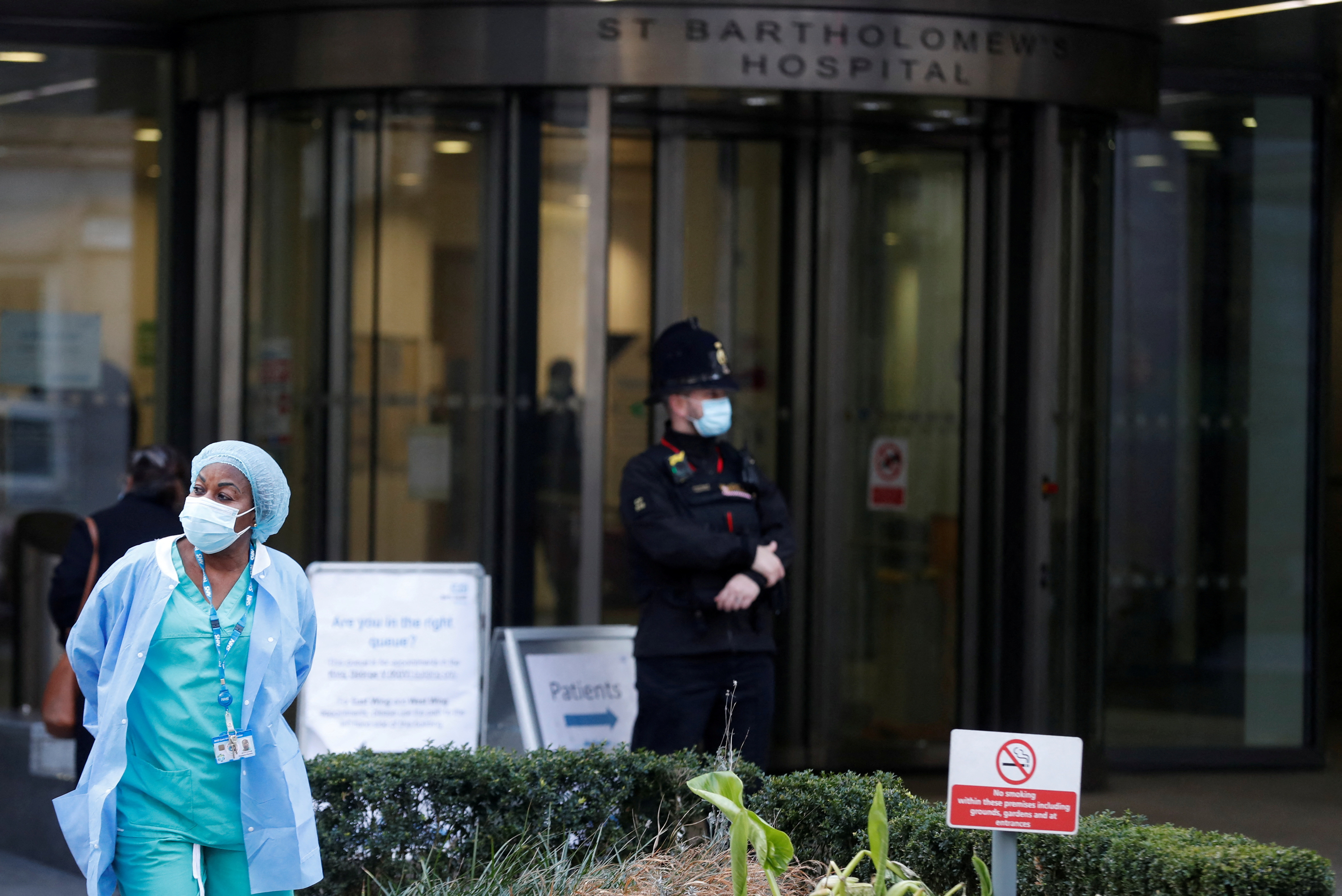 A member of NHS stuff stands outside of St Bartholomew's Hospital entrance, in London, Britain, March 1, 2021. [File:Matthew Childs/Reuters]