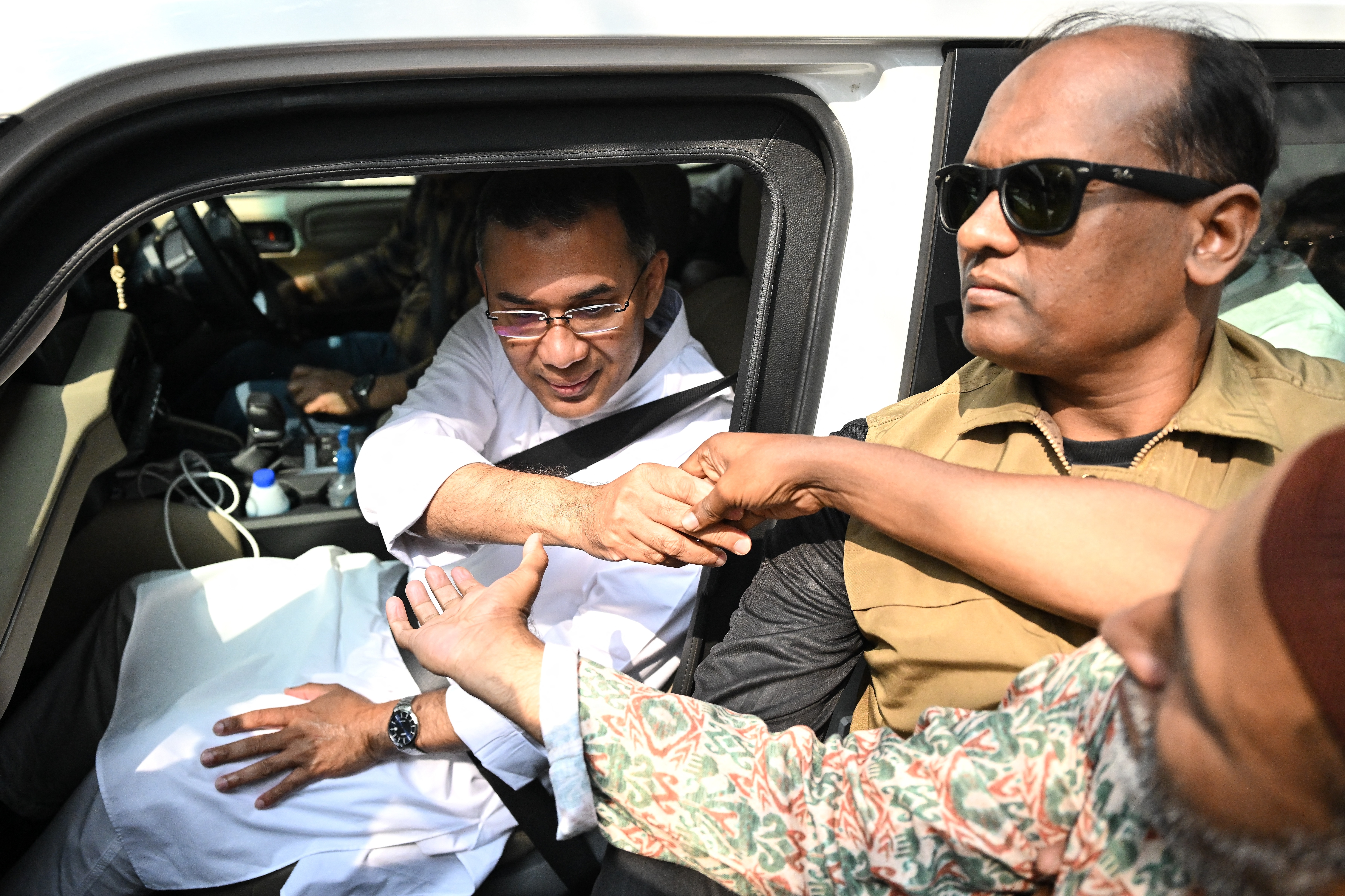 Bangladesh Nationalist Party (BNP) chairman and election candidate Tarique Rahman (L) greets his supporters as leaves his residence in Dhaka on February 13, 2026 a day after Bangladesh's general election. The Bangladesh Nationalist Party (BNP) claimed a thumping win on February 13 in the first elections held since a deadly 2024 uprising, with leader Tarique Rahman poised to become prime minister. (Photo by MUNIR UZ ZAMAN / AFP)