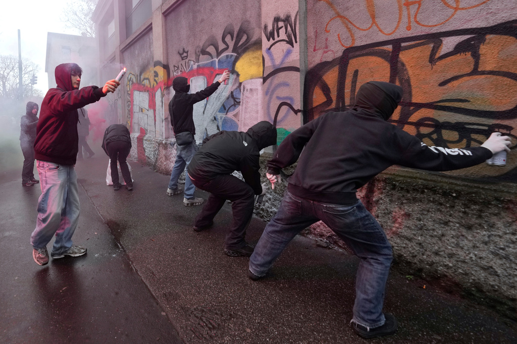 Protesters spray paint on a wall during a demonstration against ICE organized by students at the 2026 Winter Olympics, in Milan, Italy, Friday, Feb. 6, 2026. (AP Photo/Luca Bruno)