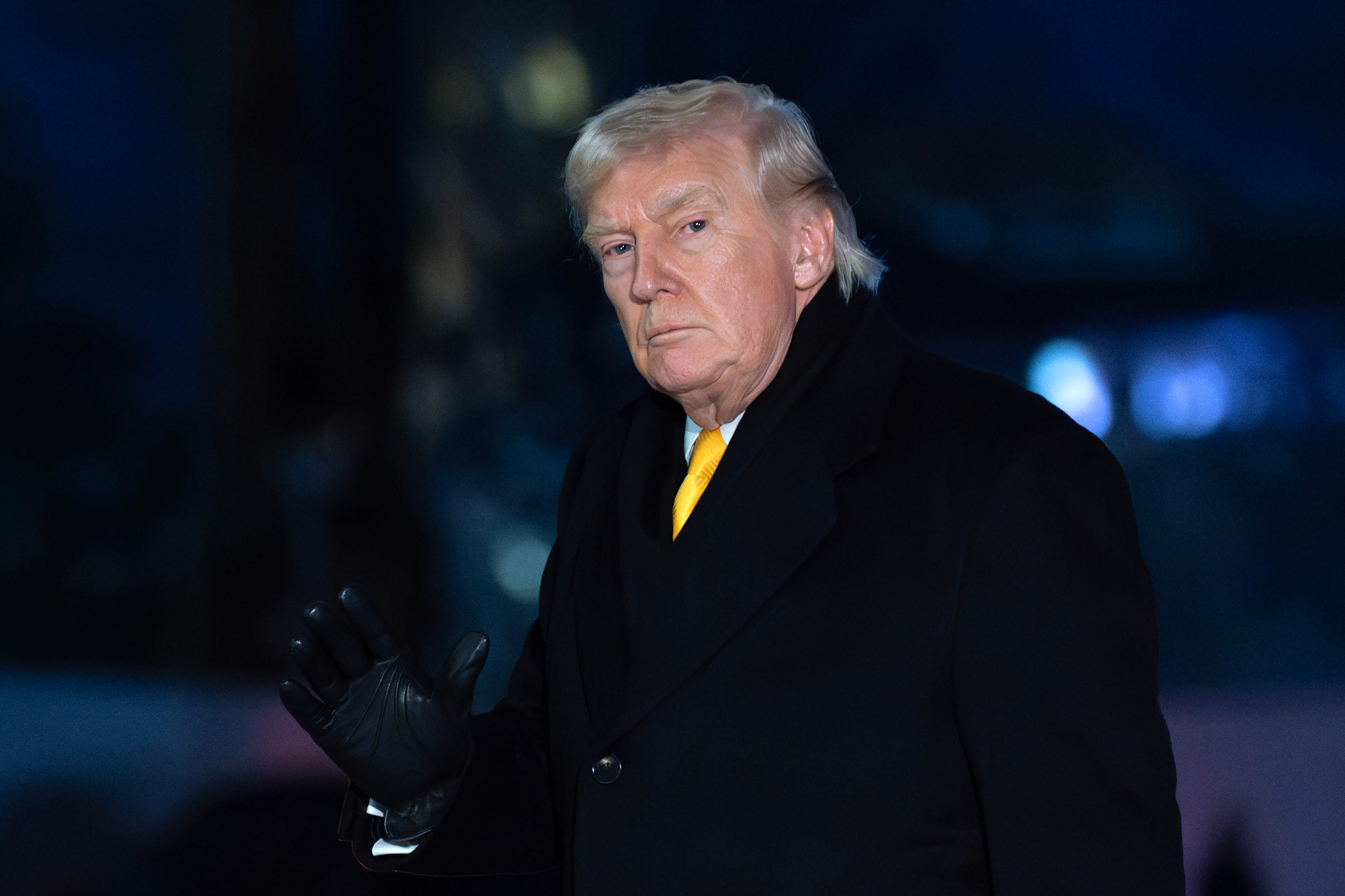 Donald Trump walks at night across the White House lawn
