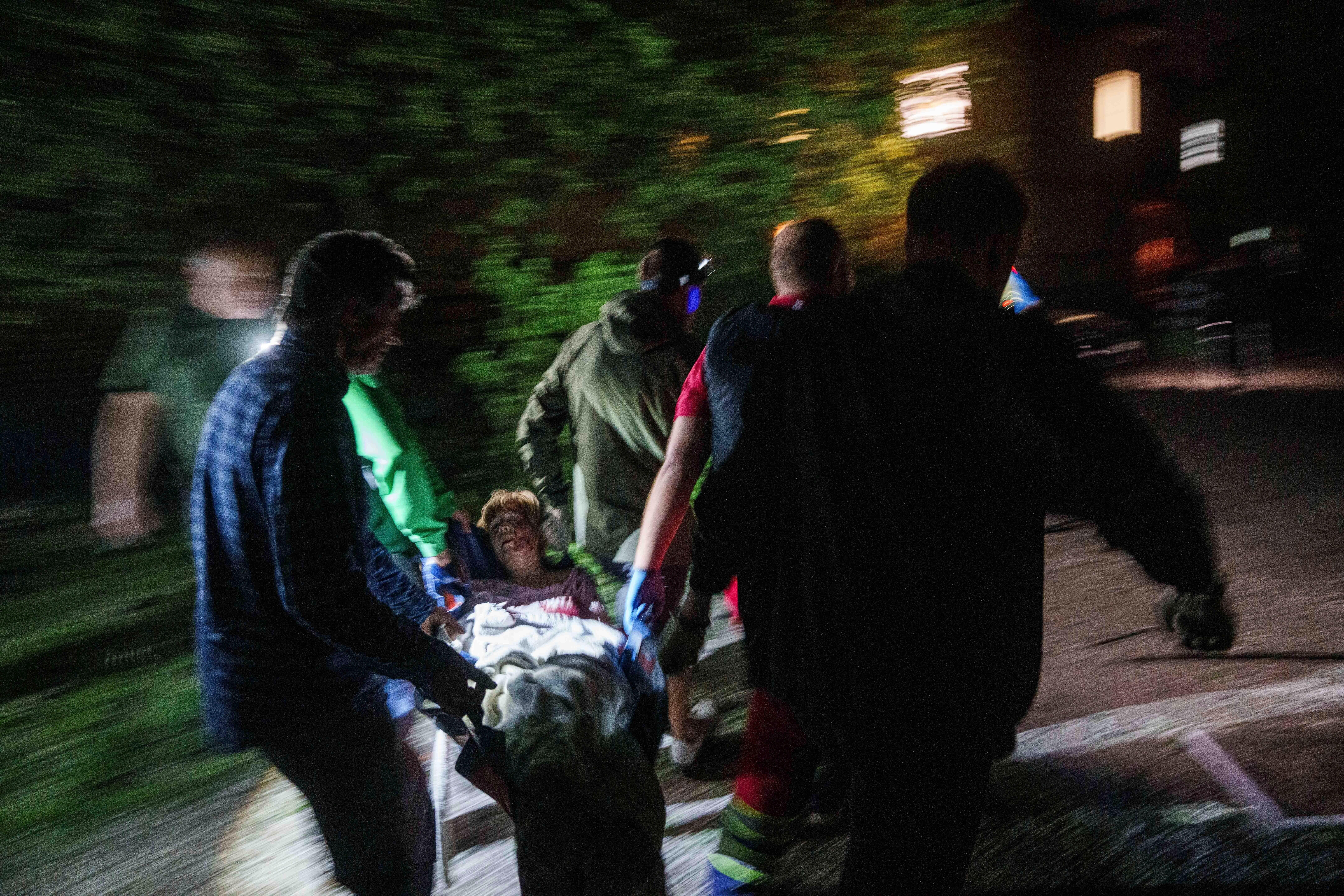 Rescue workers carry an injured woman on a stretcher out of a house destroyed by a Russian airstrike in a residential neighbourhood in Kyiv