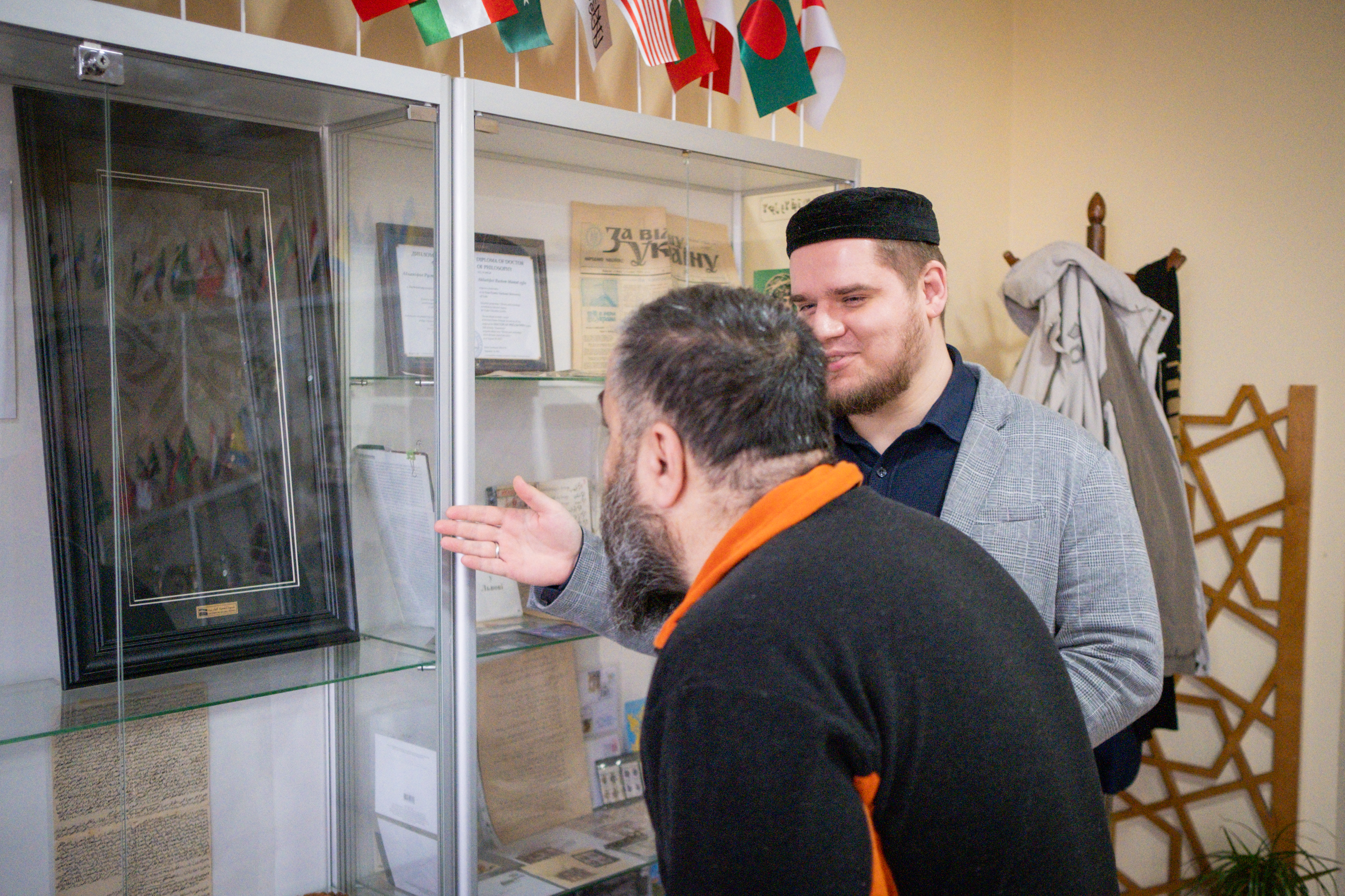 Zhumabekov motions to a small piece of the Kiswa, the black cloth that covers the Kaaba in Mecca, which has been framed and put in a display cabinet, Lviv, Ukraine, January 29 2026 [Nils Adler/Al Jazeera]