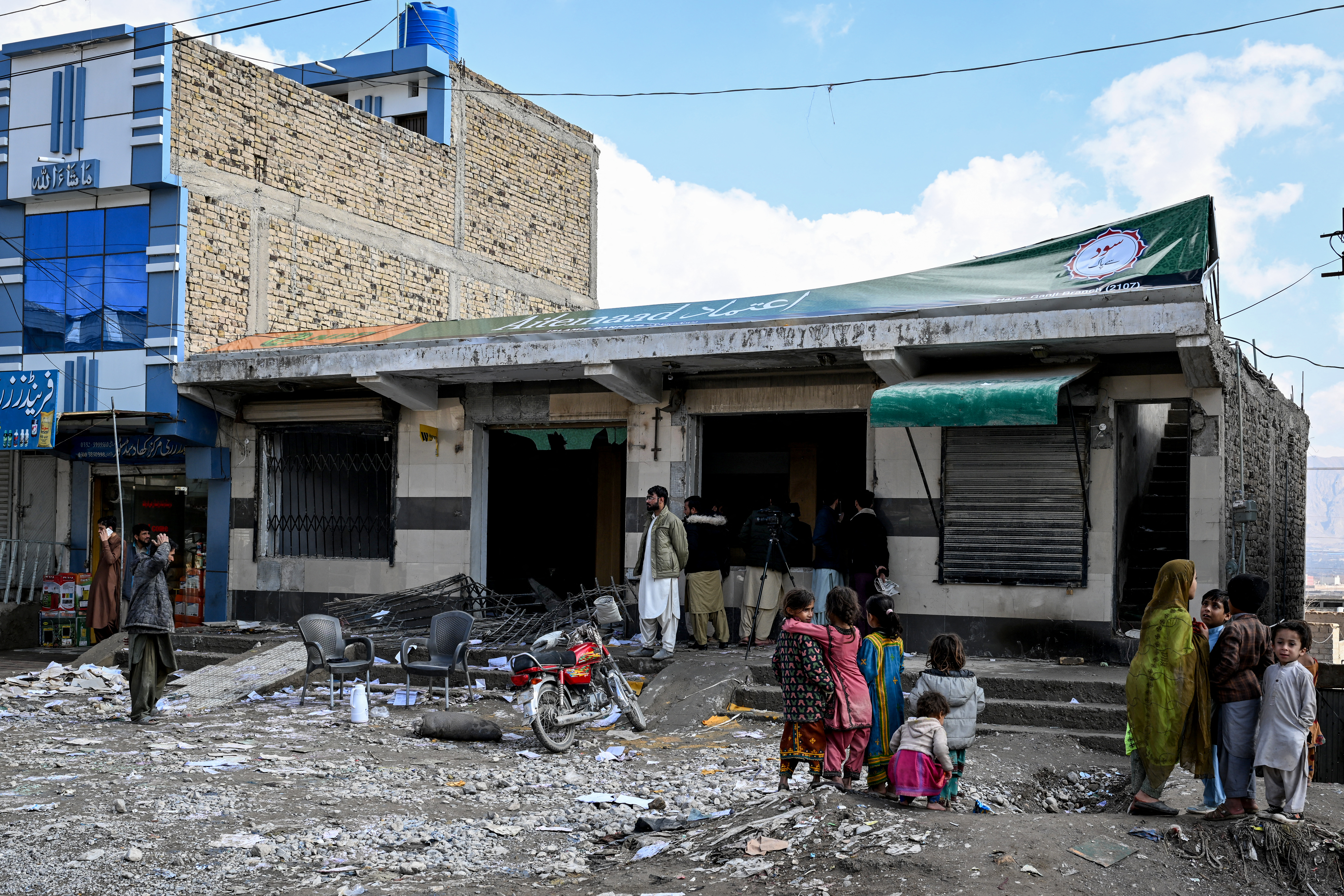Local residents look at a damaged bank on the outskirts of Quetta on February 1, 2026 a day after an attack by Baloch separatists.
