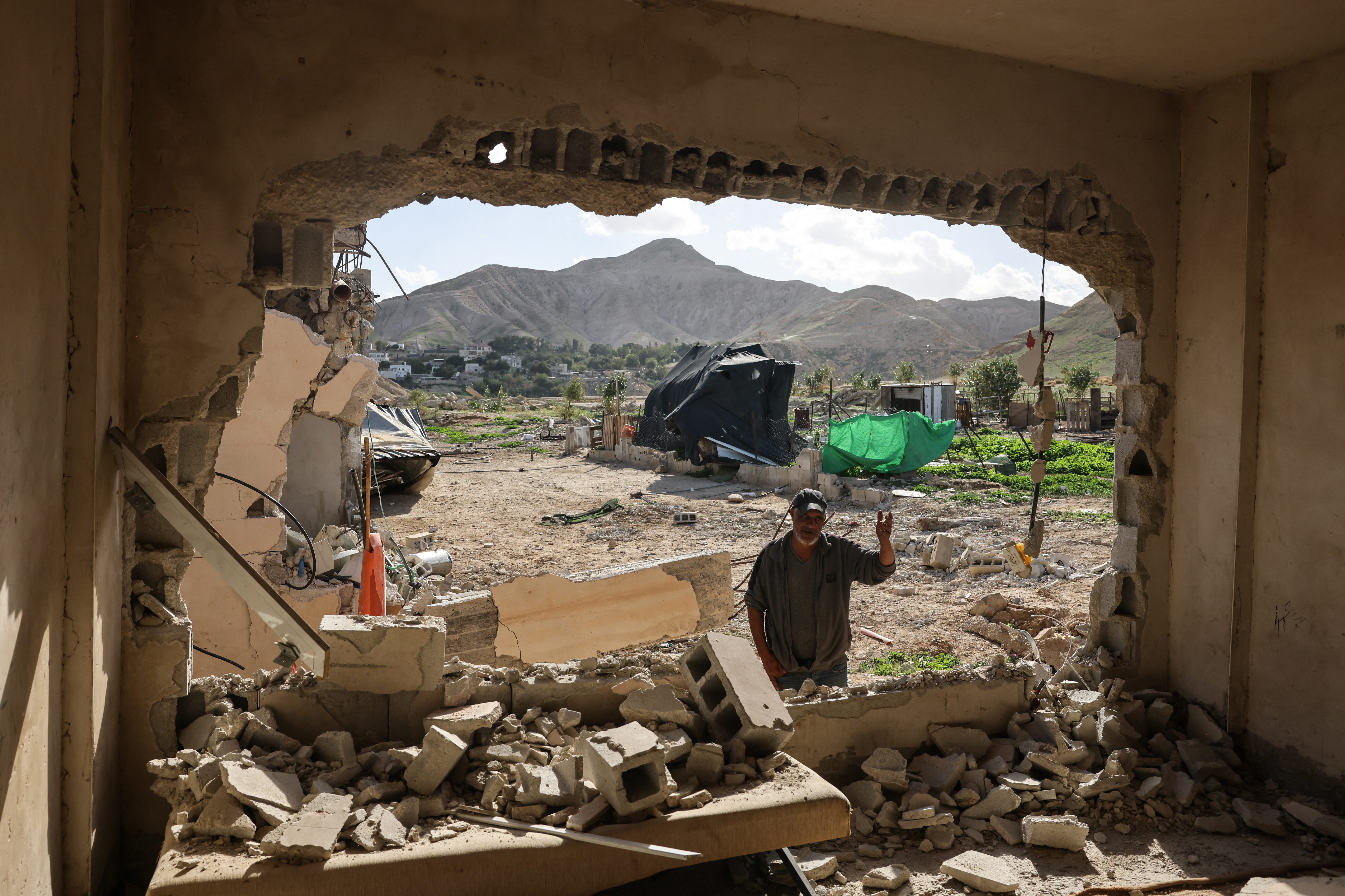A Palestinian man stands in front of a house that was reportedly demolished by Israeli settlers the previous day in a village on the outskirts of Jericho, in the Israeli-occupied West Bank, on February 11, 2026.