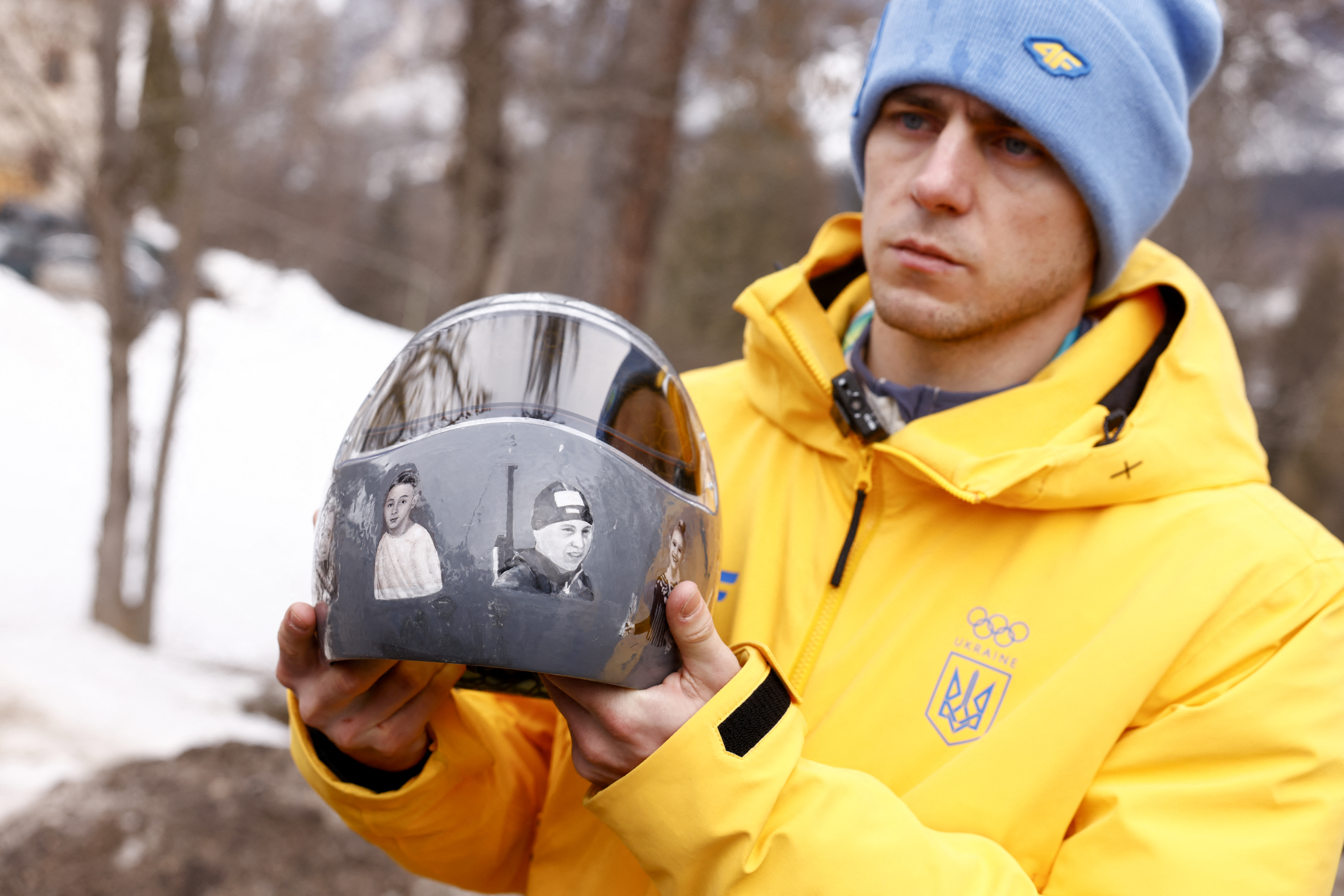 Ukraine's skeleton racer Vladyslav Heraskevych holds his helmet, which depicts victims of his country's war with Russia, in Cortina d'Ampezzo on February 12, 2026