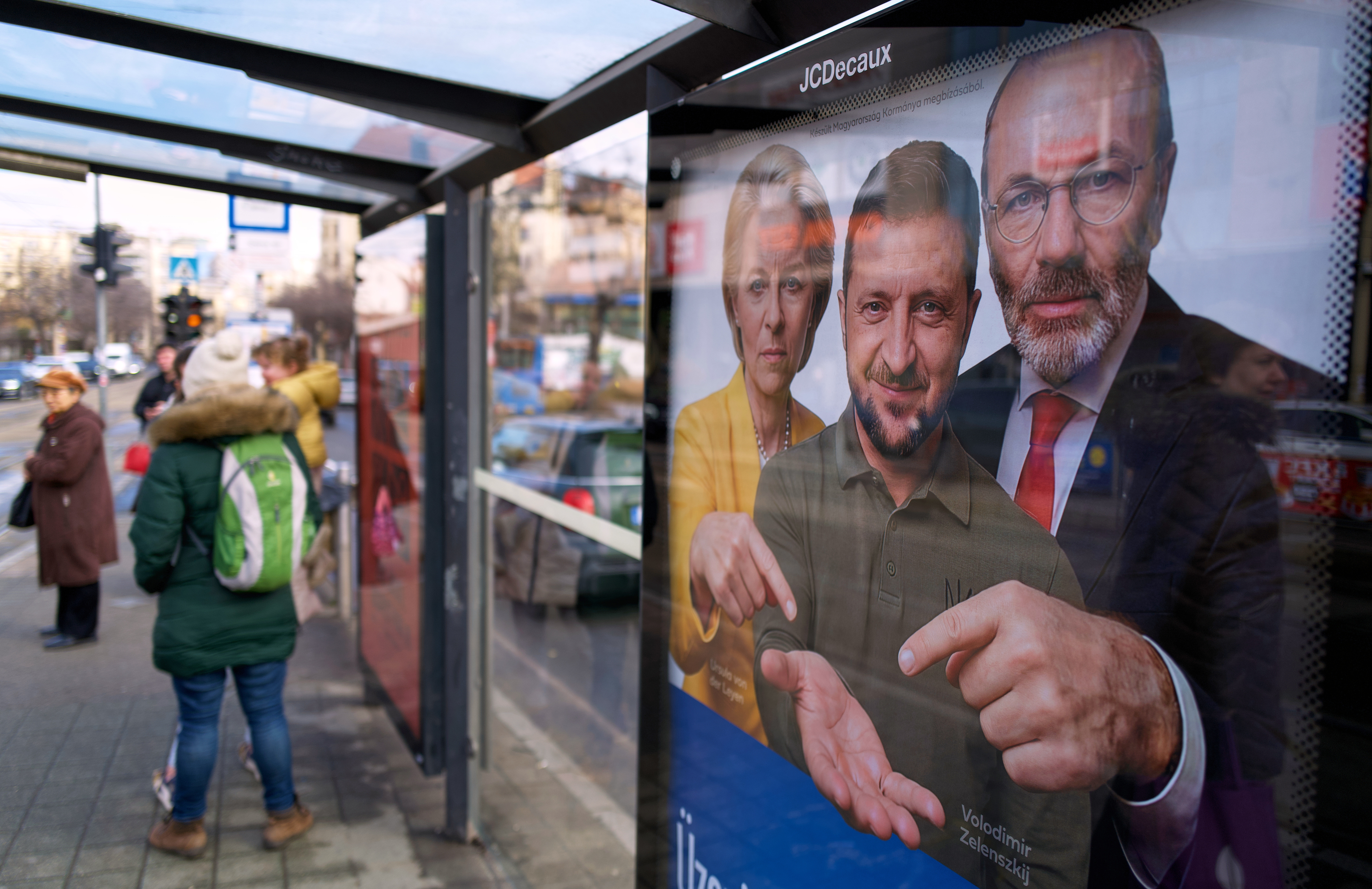 A billboard showing an AI-generated image of Ukrainian President Volodymyr Zelenskyy, center, flanked by European officials is displayed at a bus stop in Budapest, Hungary, Monday, Feb. 23, 2026. (AP Photo/Bela Szandelszky)