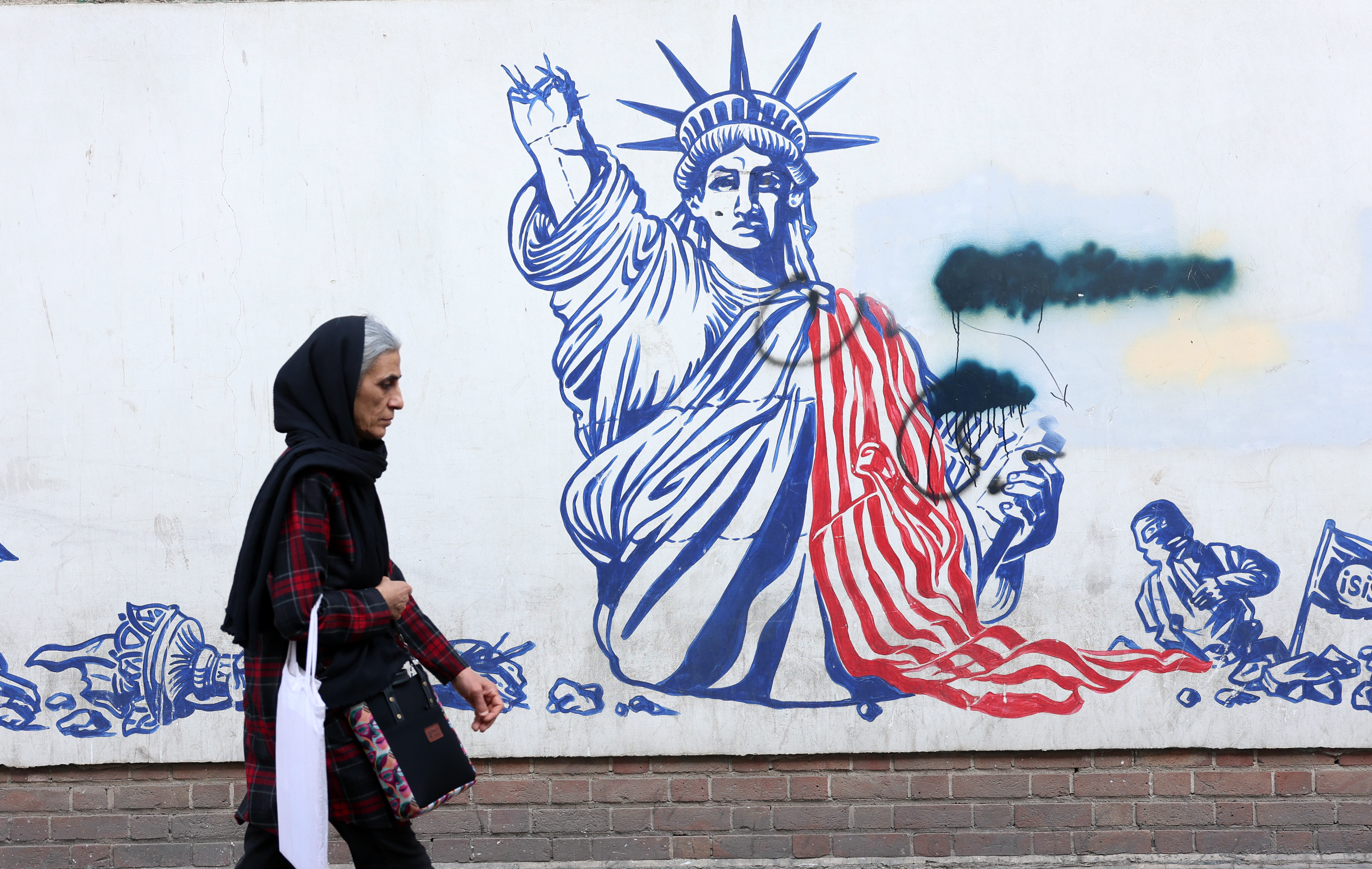 epa12770848 An elderly Iranian woman walks next to an anti-US mural in Tehran, Iran, 23 February 2026. According to a statement by the Omani Foreign Minister on X (formerly Twitter), Iran and the US are expected to hold another round of talks on 26 February 2026 in Geneva, Switzerland, to resume nuclear negotiations. EPA/ABEDIN TAHERKENAREH
